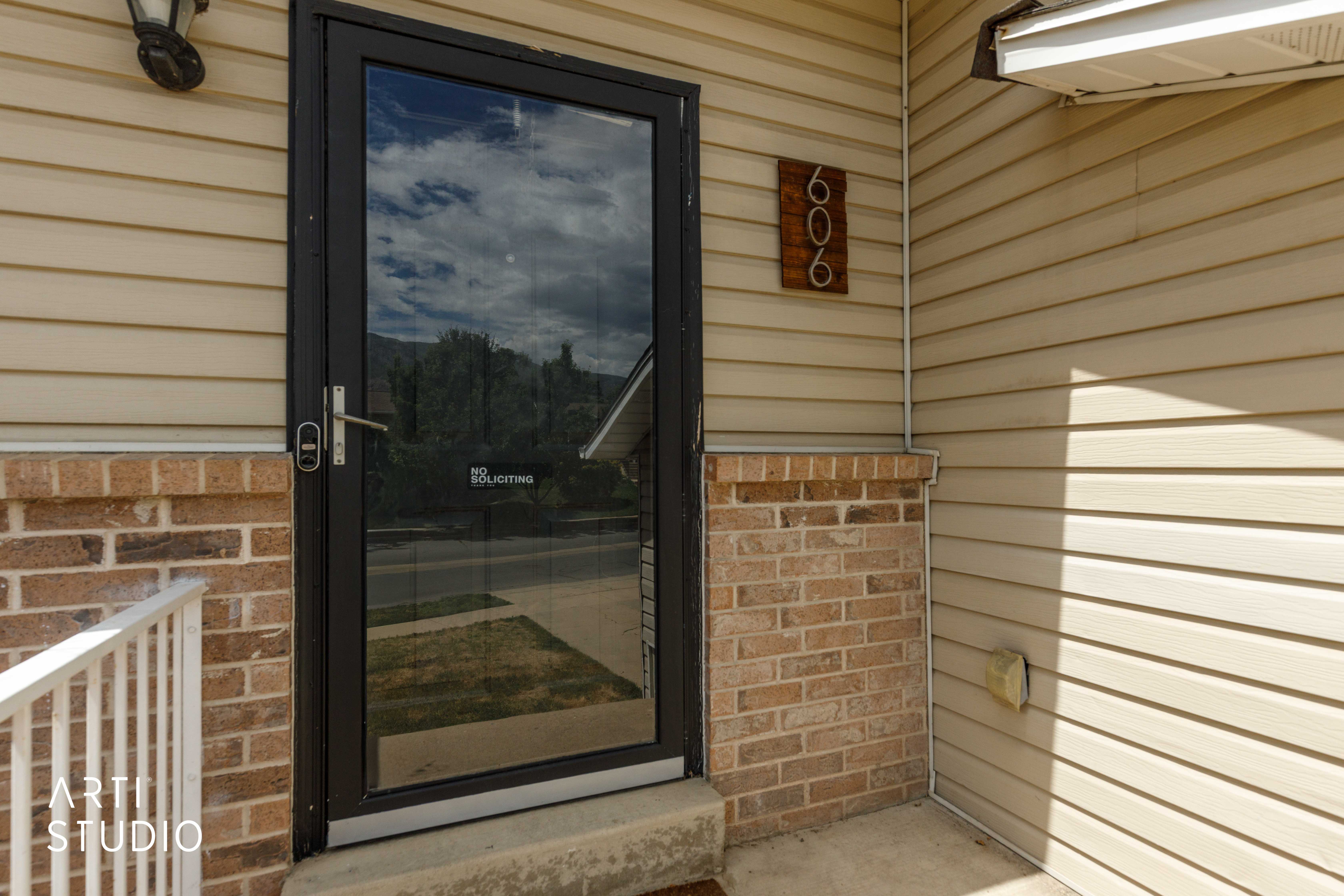 Front entry featuring a dark-framed storm door and sconce lighting