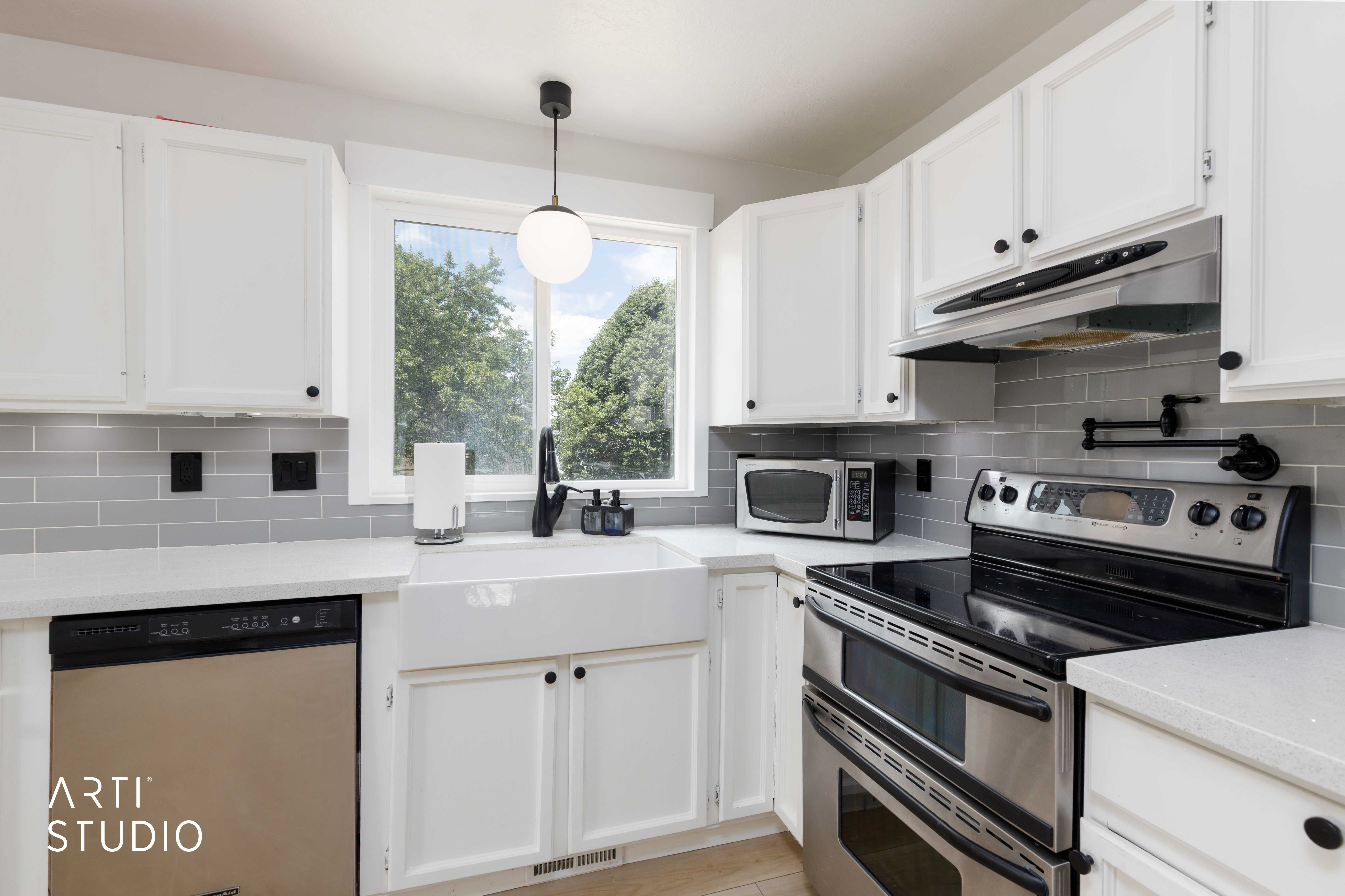 Modern kitchen featuring white cabinetry, quartz countertops, a white farmhouse sink, and stainless steel appliances including a dishwasher and range with a double oven