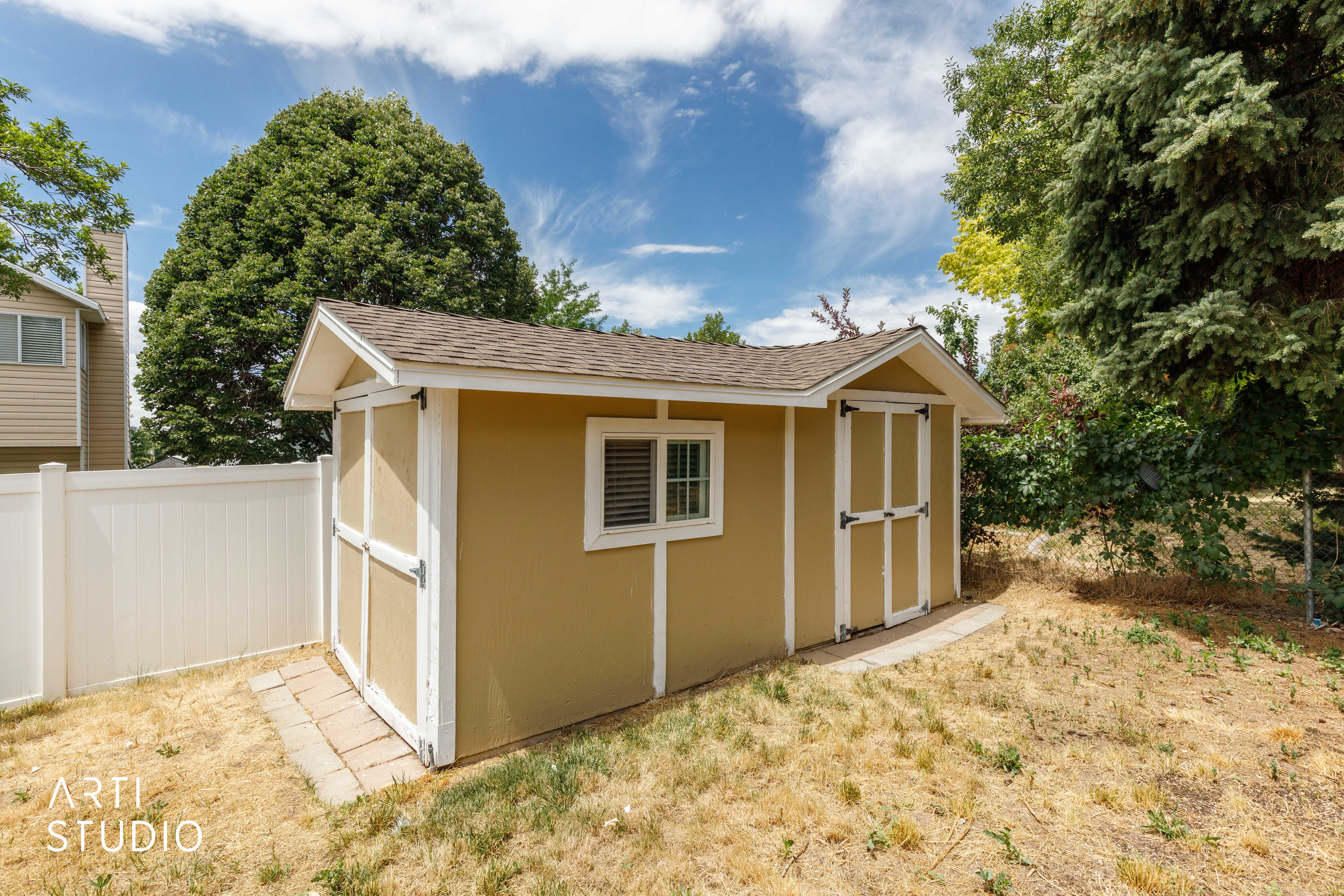 Detached shed featuring a gabled roof, a window with grilles, double entry doors, and a neutral-toned exterior