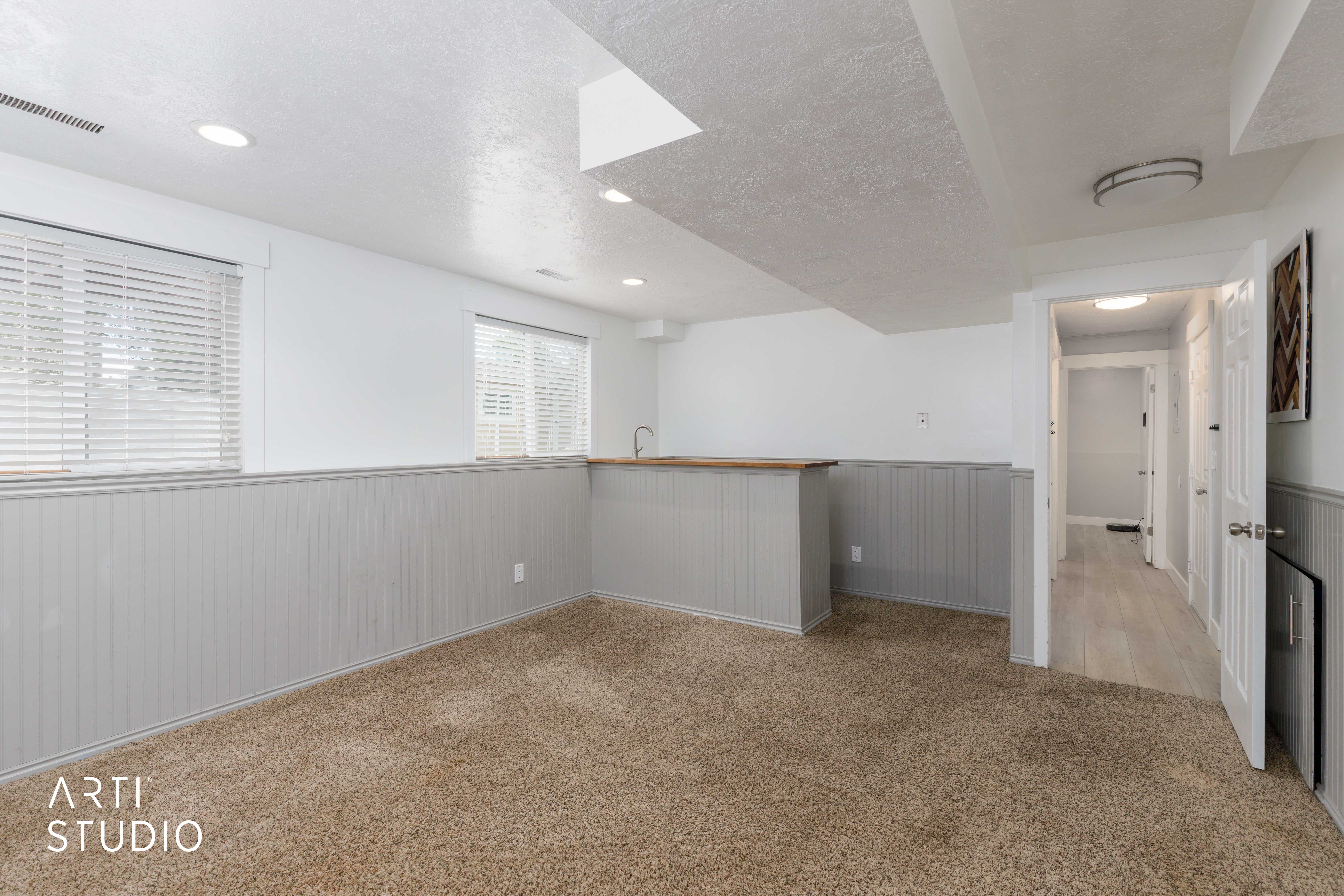 Recessed lighting illuminating a spacious carpeted room with beadboard wainscoting