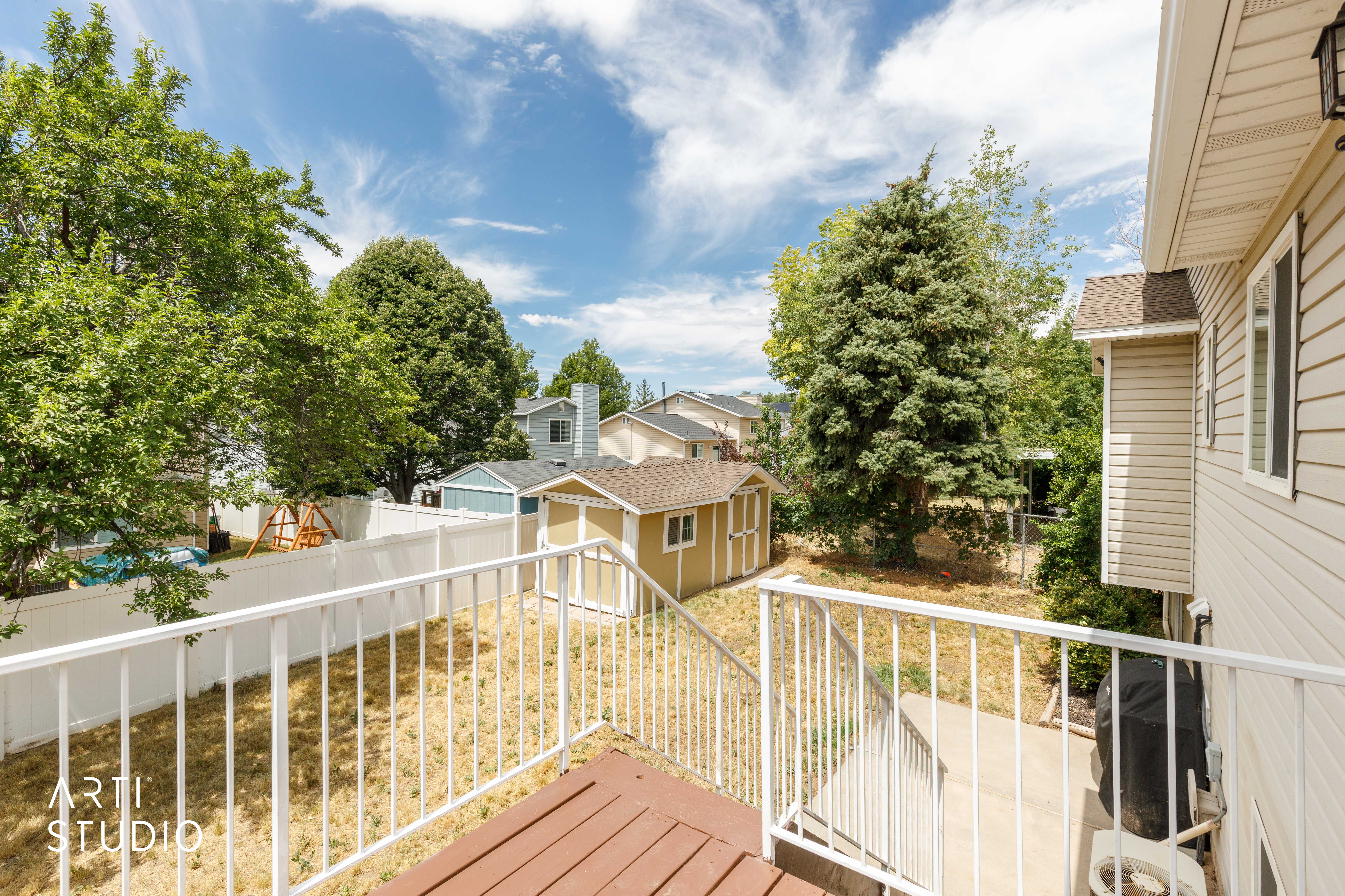 Raised deck with a white railing overlooking the backyard