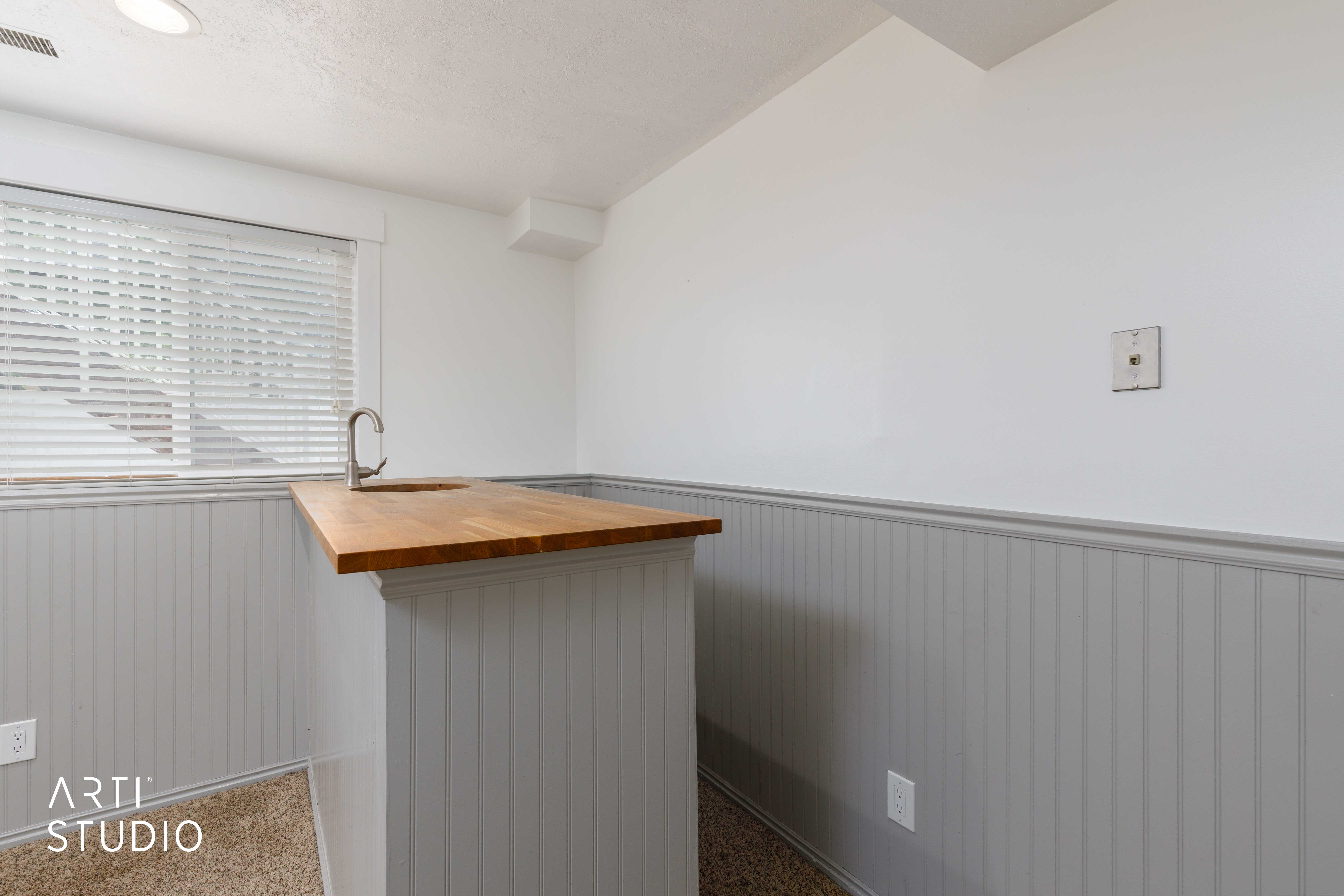 Built-in wet bar featuring a wood-finish countertop, undermount sink with a gooseneck faucet, and beadboard paneling
