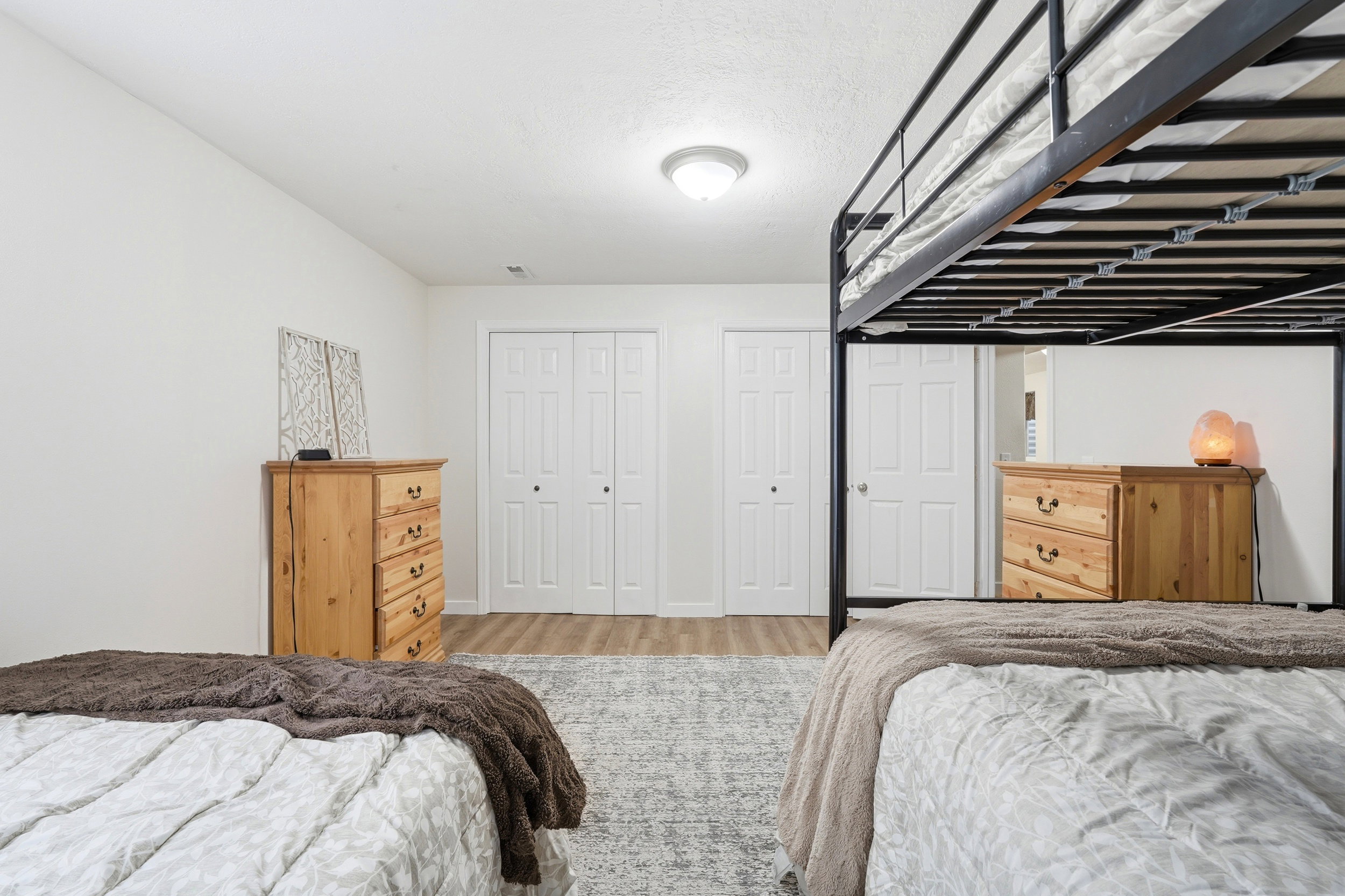 Bedroom featuring wood-finish flooring, a neutral color palette, and multiple paneled doors