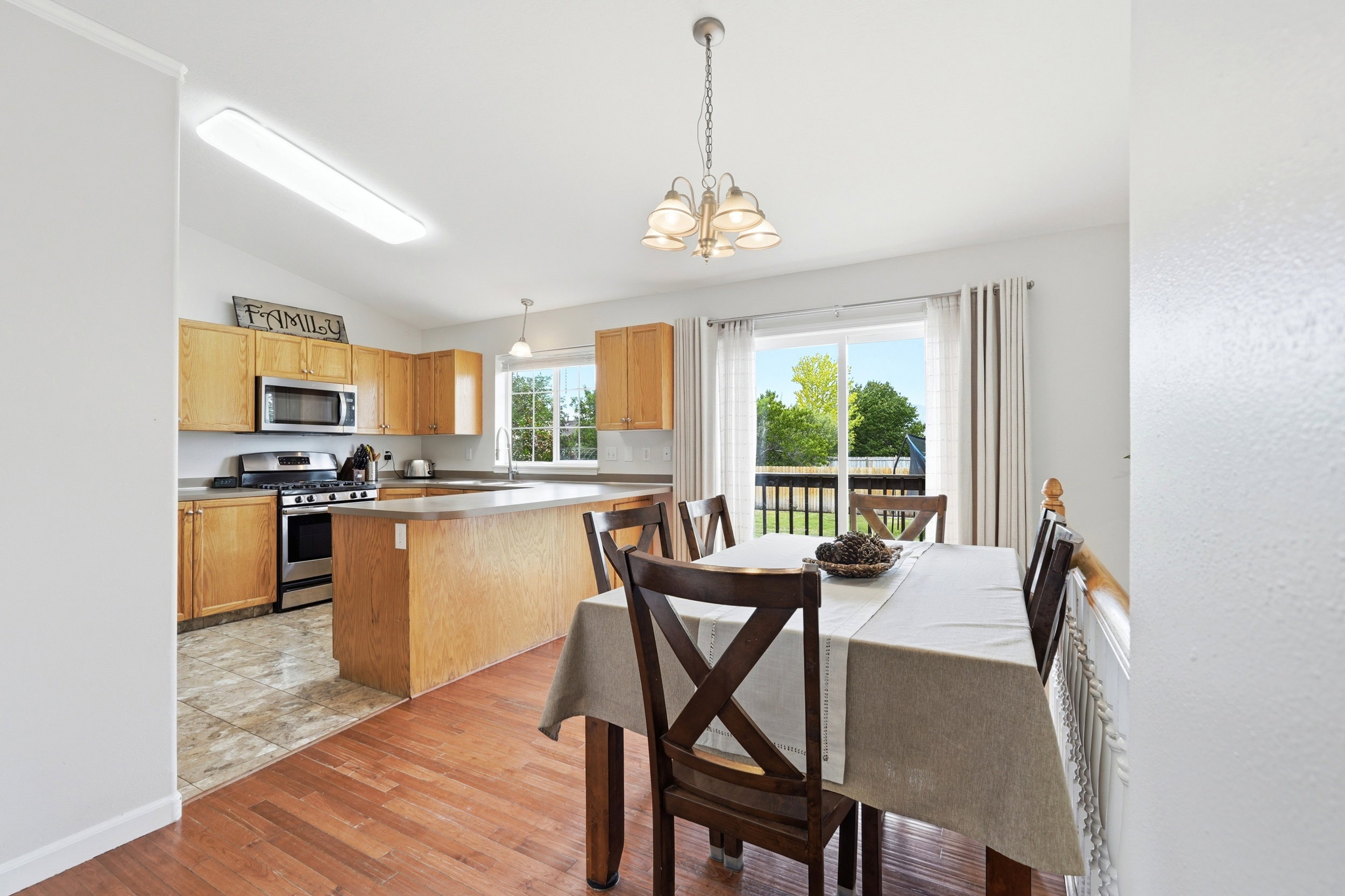 Kitchen and dining area featuring light wood cabinetry, stainless steel appliances, a center island with countertop seating, and a sliding glass door leading to a deck