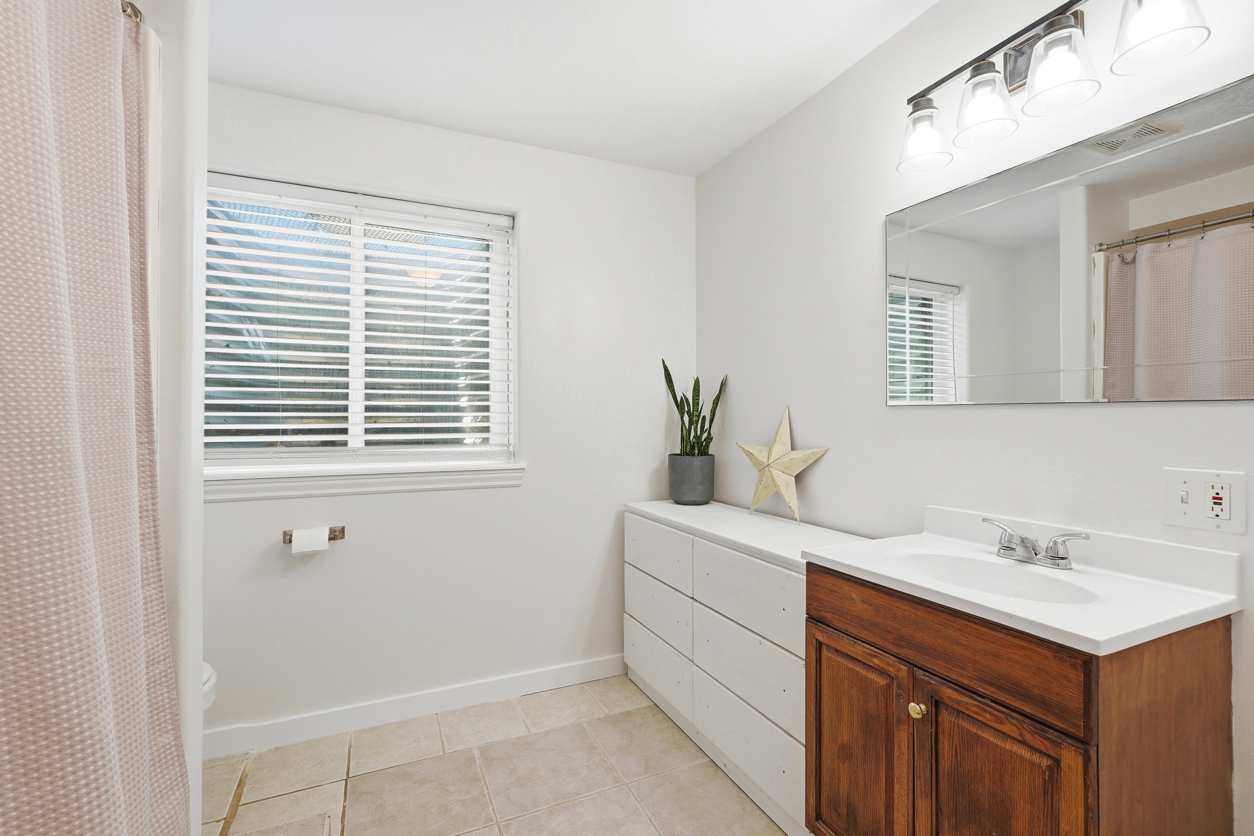 Bathroom featuring a wood-finish vanity with an integrated sink and a white countertop