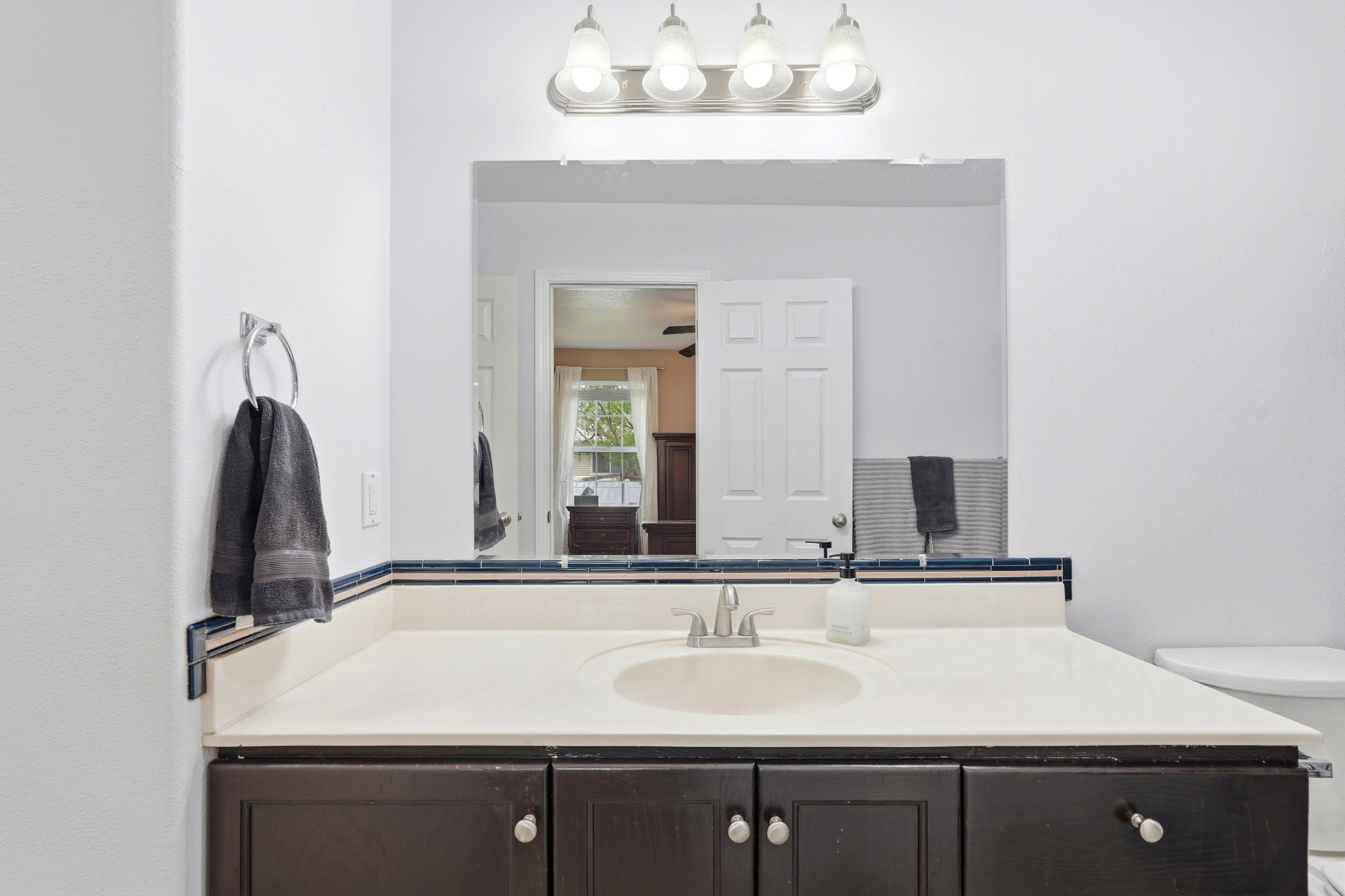 Bathroom vanity featuring a light-toned countertop with an integrated sink, dark wood-finish cabinetry, and a chrome faucet