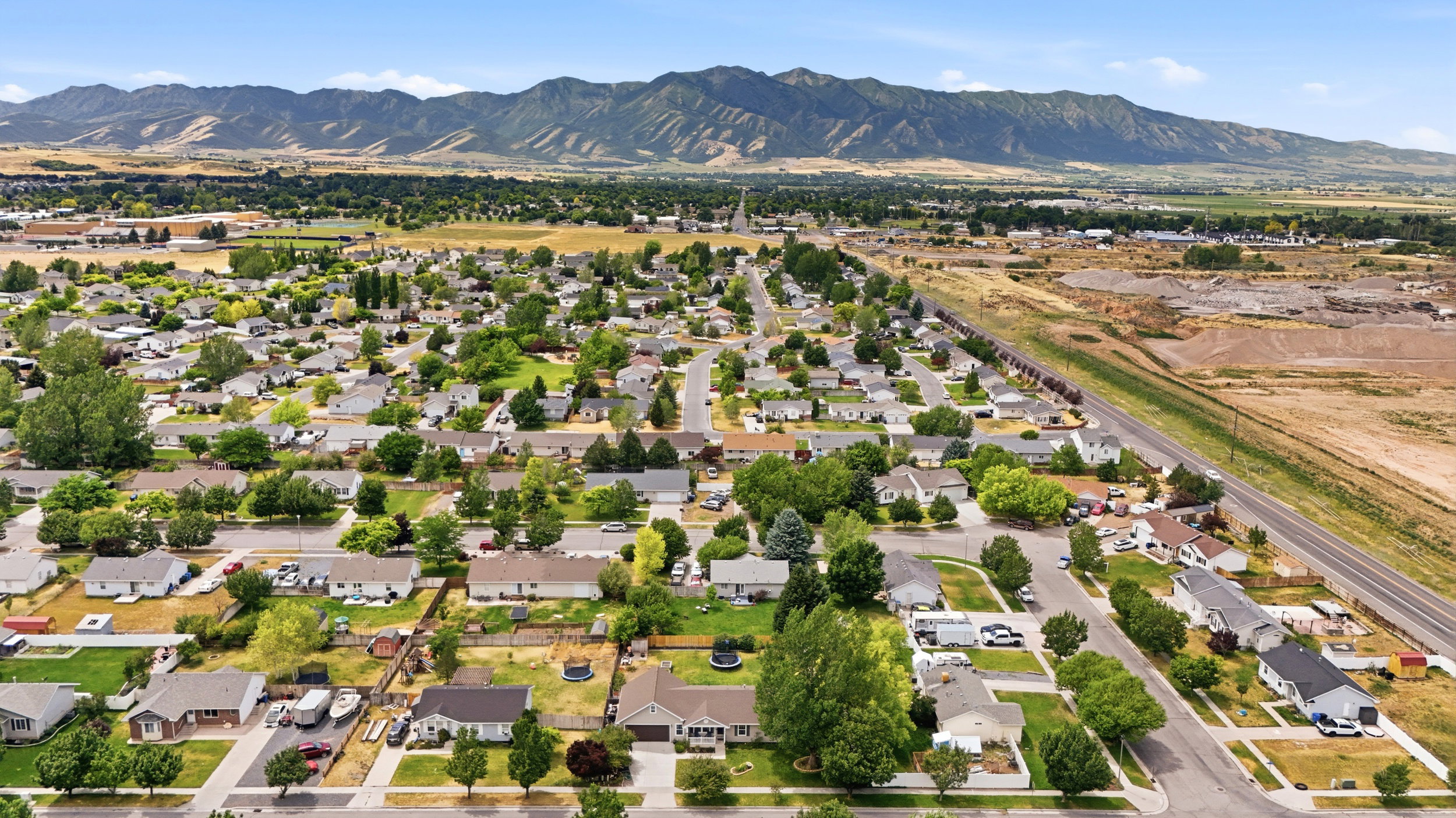 Aerial perspective showcasing a residential neighborhood with established trees and mountain backdrop