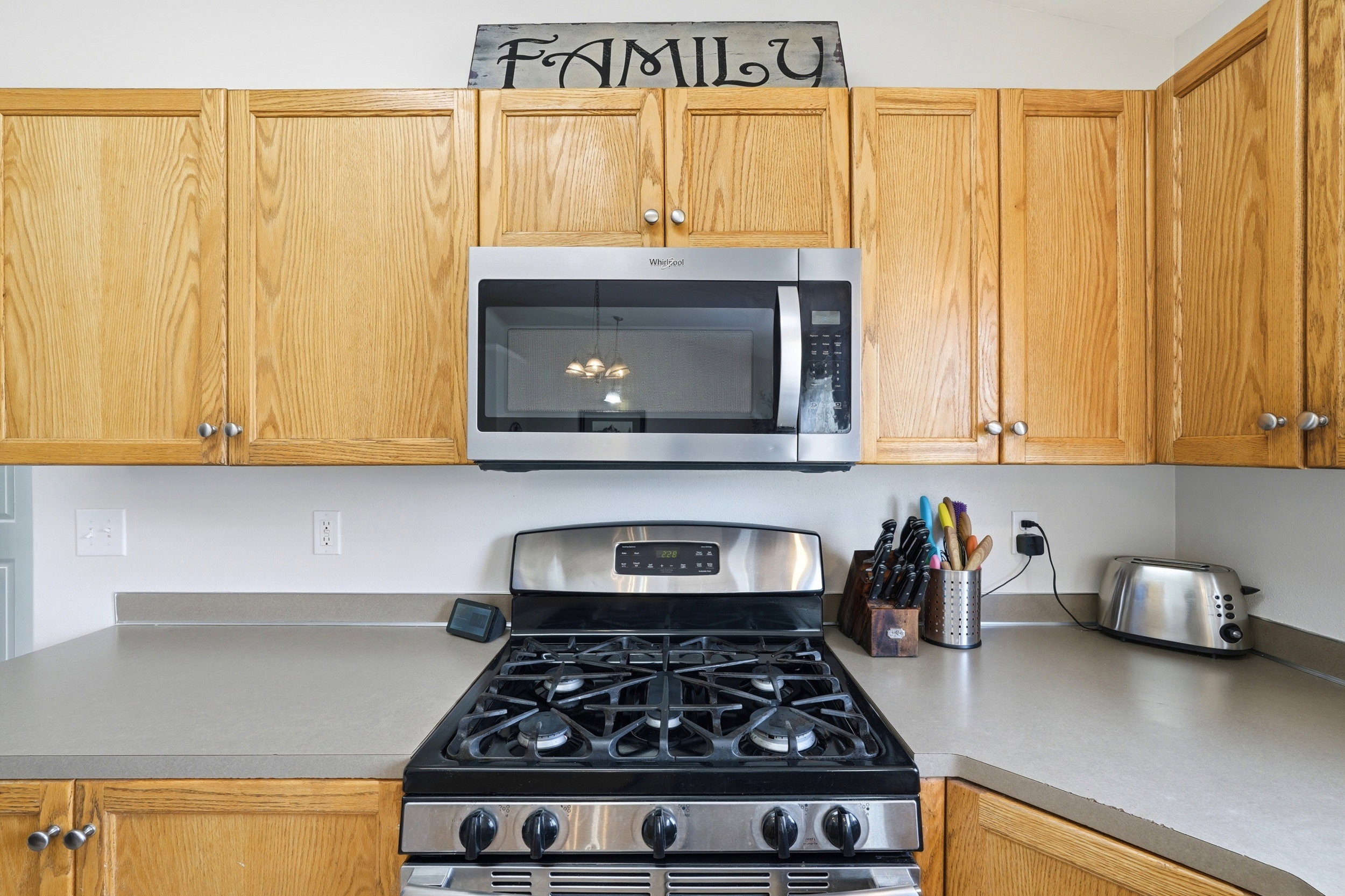 Kitchen featuring natural wood cabinetry, stainless steel oven with gas cooktop, over-the-range microwave, and light-toned countertops