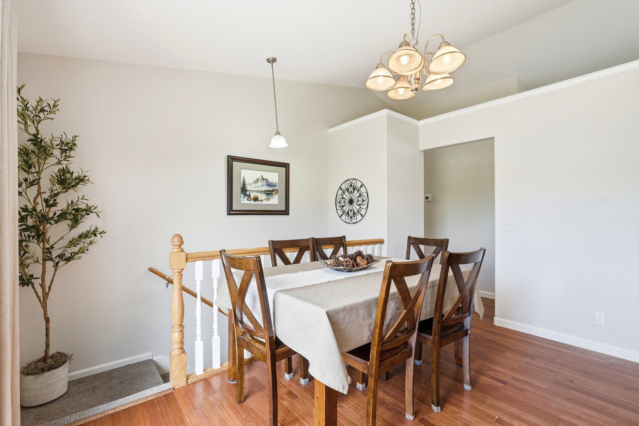 Hardwood-finish flooring extending into the dining area with a multi-light chandelier