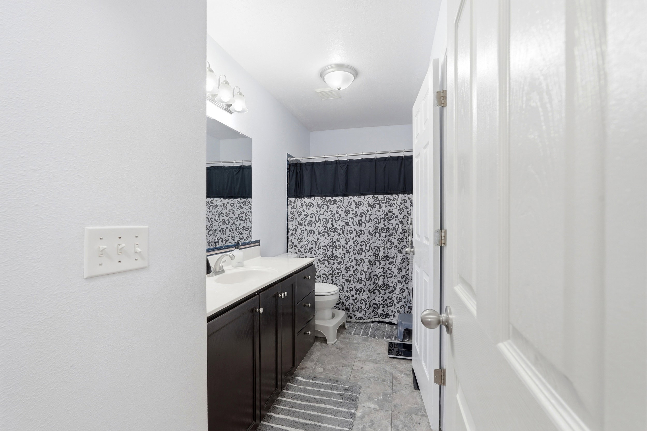 Bathroom featuring a dark wood vanity with a white countertop and integrated sink, a rectangular mirror, and overhead lighting