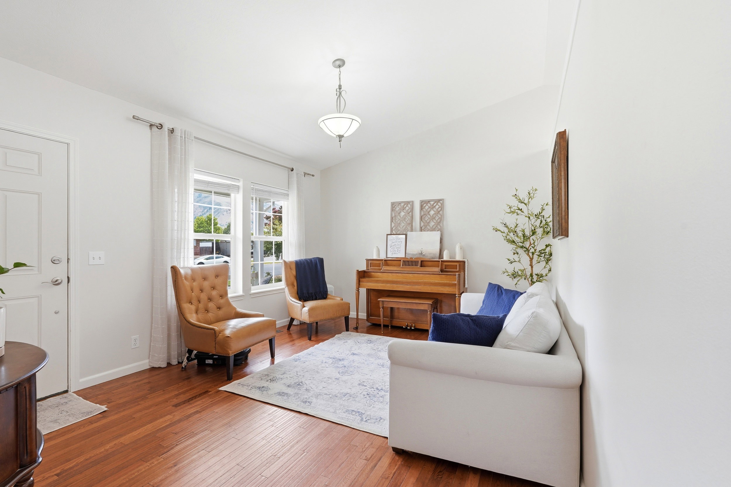 Entry area featuring a solid white door, wood-finish flooring, two large windows, white walls, and a ceiling light fixture