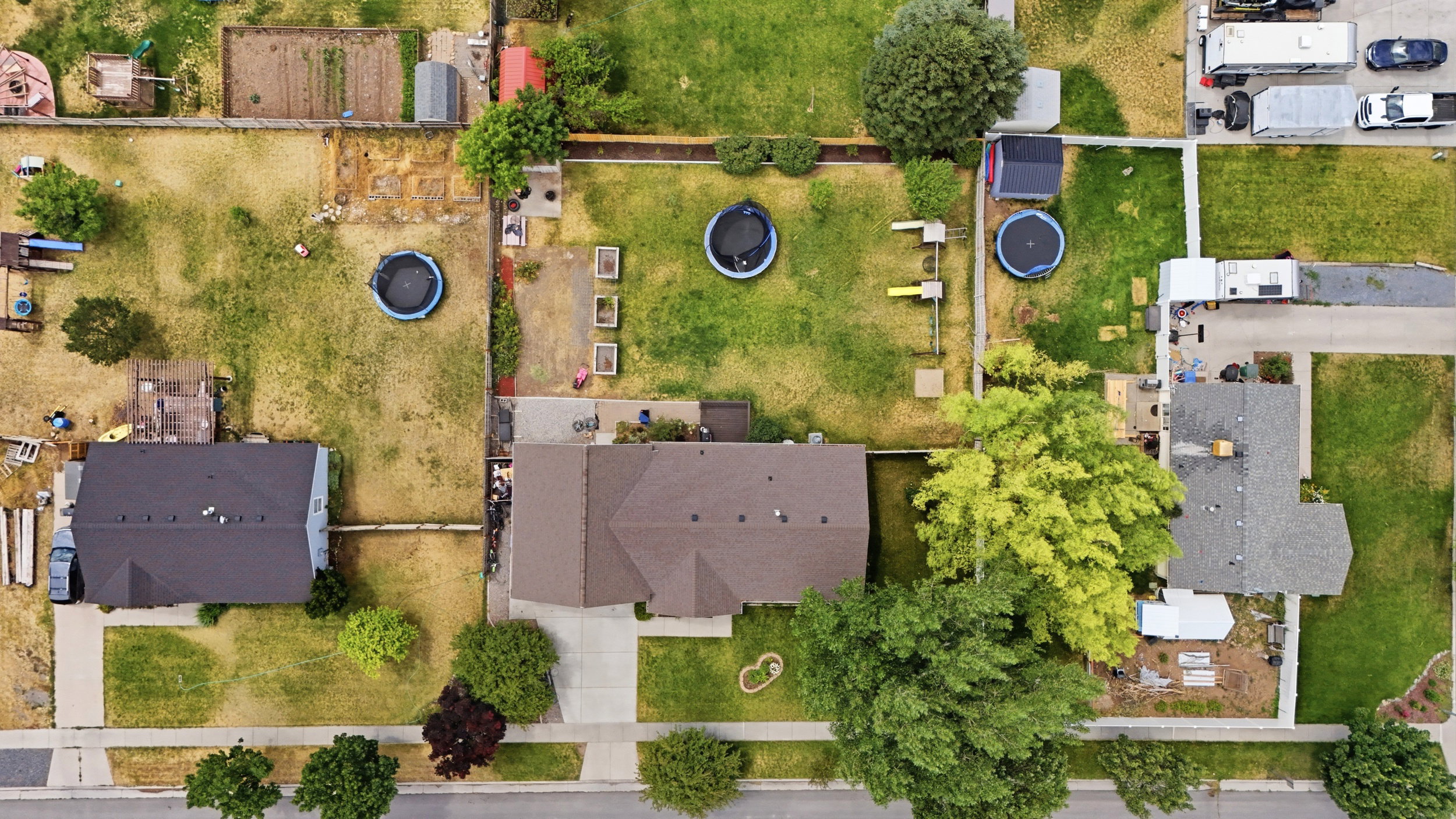 Aerial perspective showcasing a residential property with a dark shingle roof and an attached concrete driveway