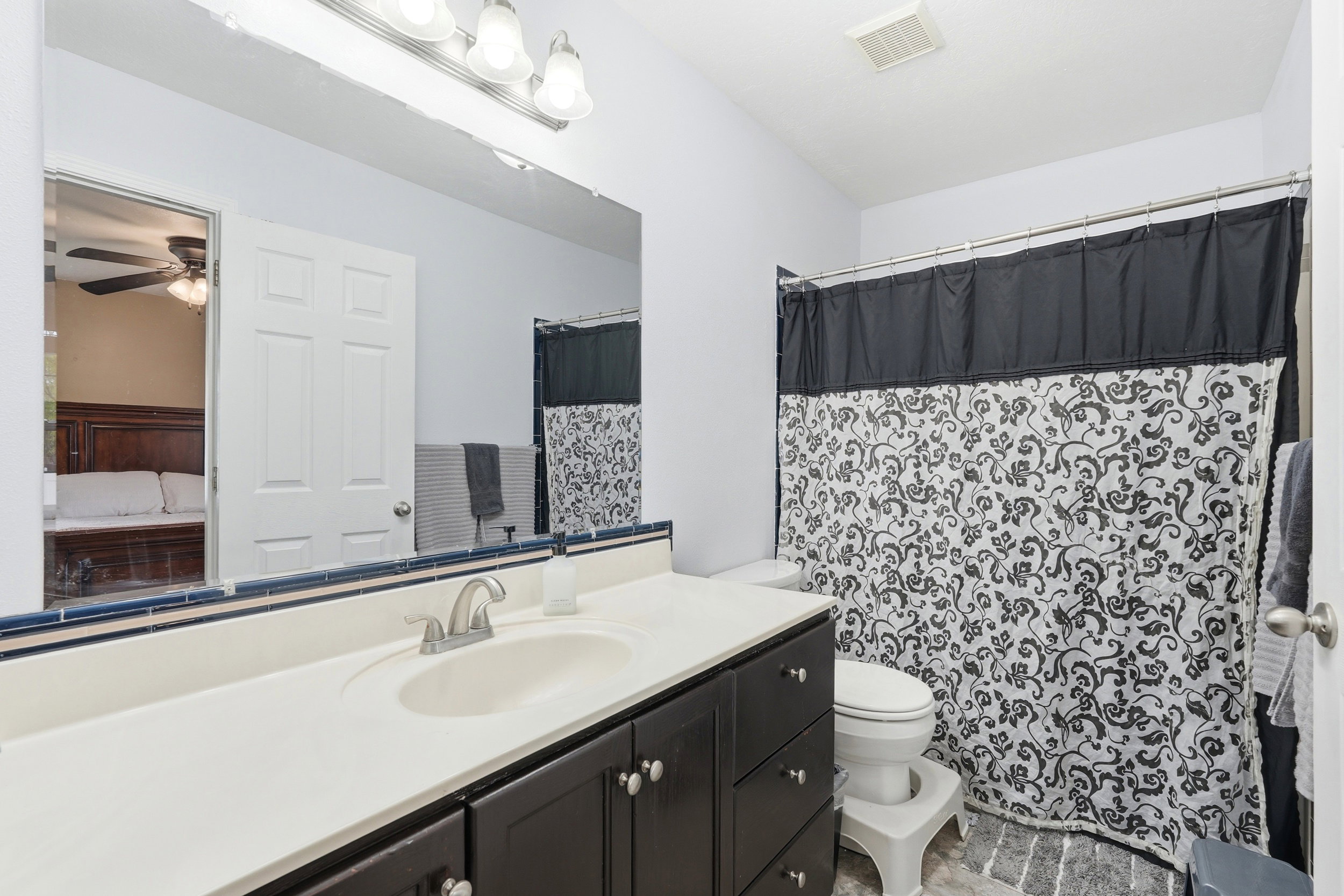 Bathroom featuring a dark wood-finish vanity with a light-toned countertop, an undermount sink, and a brushed nickel faucet