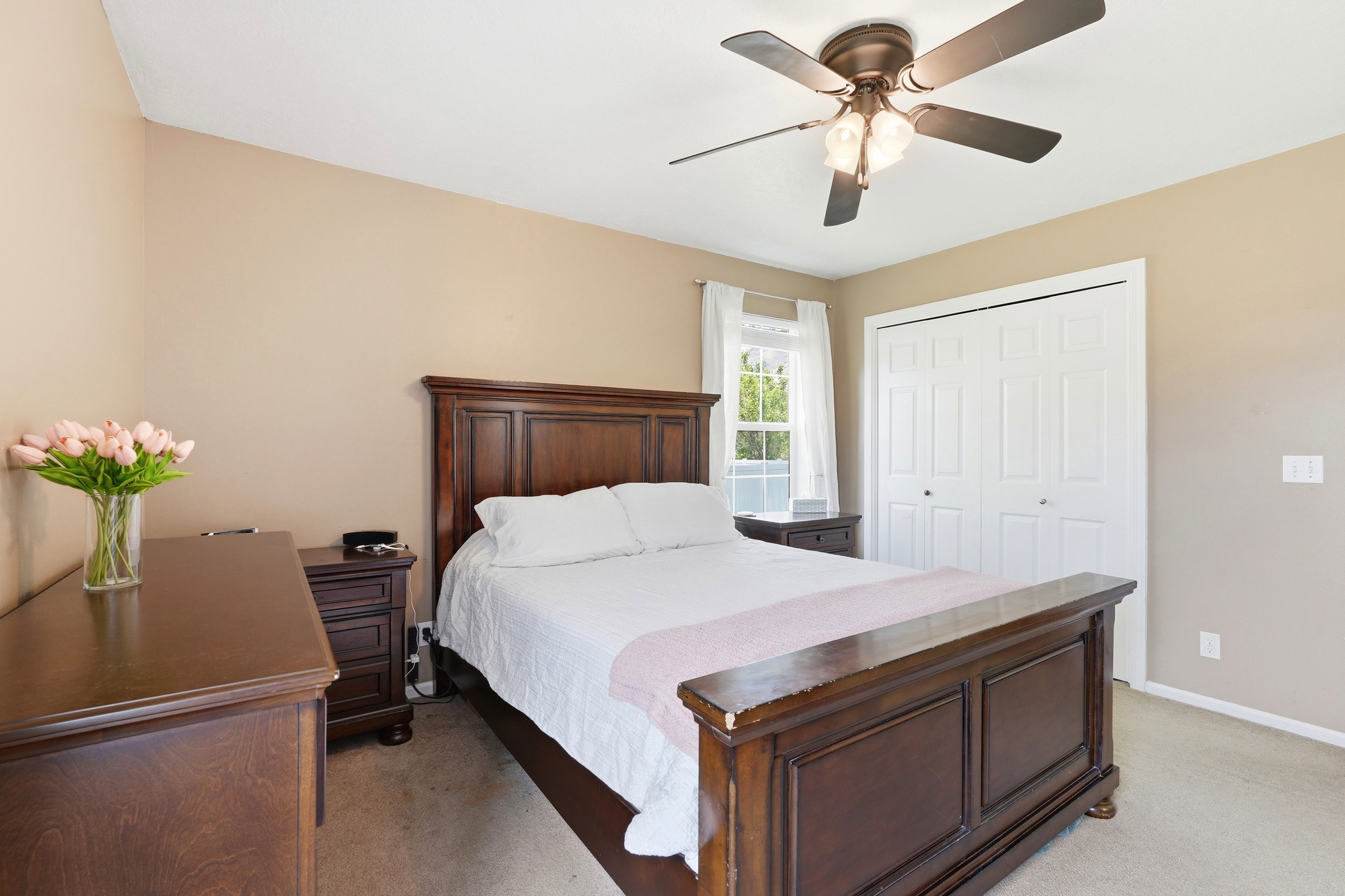 Carpeted bedroom featuring a window with white blinds and sheer curtains