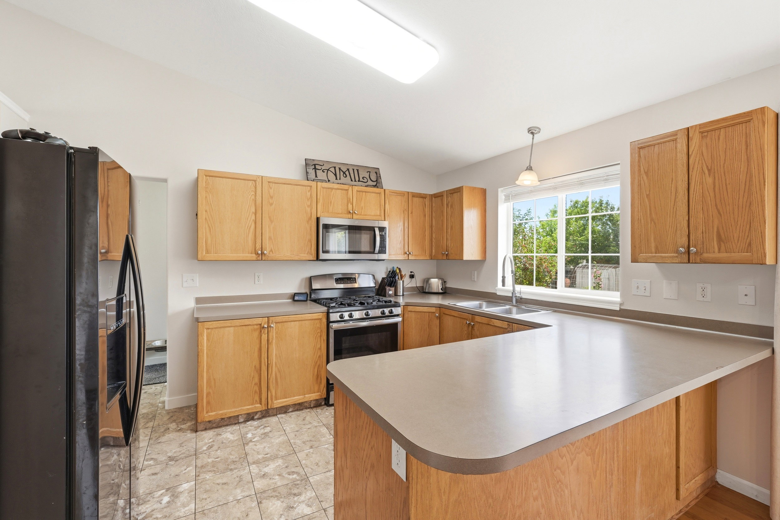 Kitchen featuring wood cabinetry, solid surface countertops, stainless steel appliances, and tile flooring