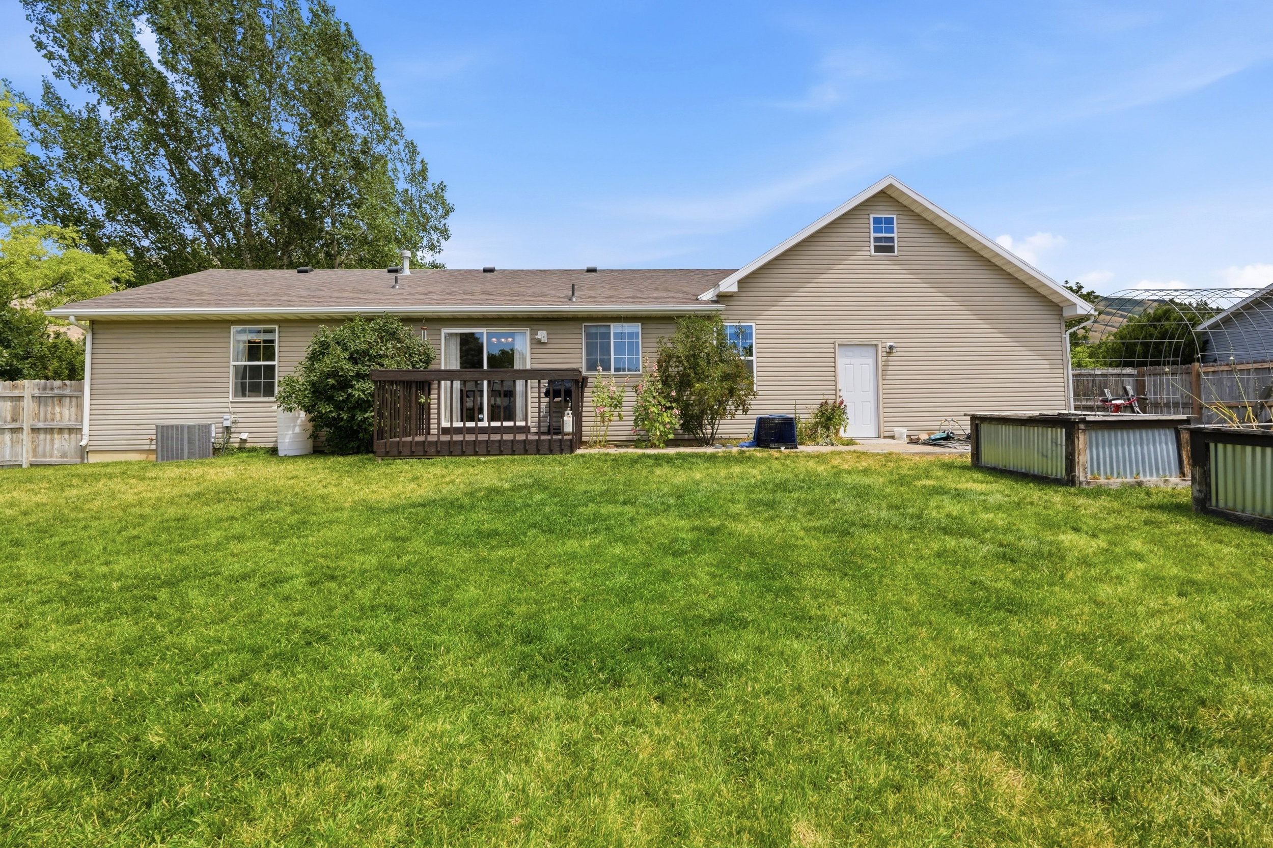 Expansive green lawn with a brown wood-finish deck