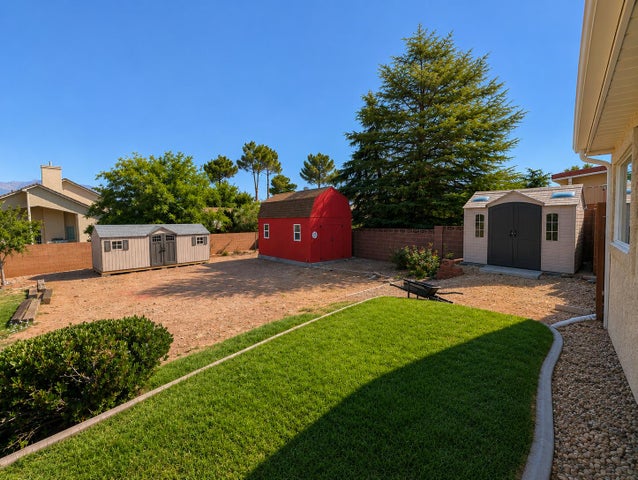 Rear property featuring a manicured lawn area, gravel landscaping, and a substantial mature tree