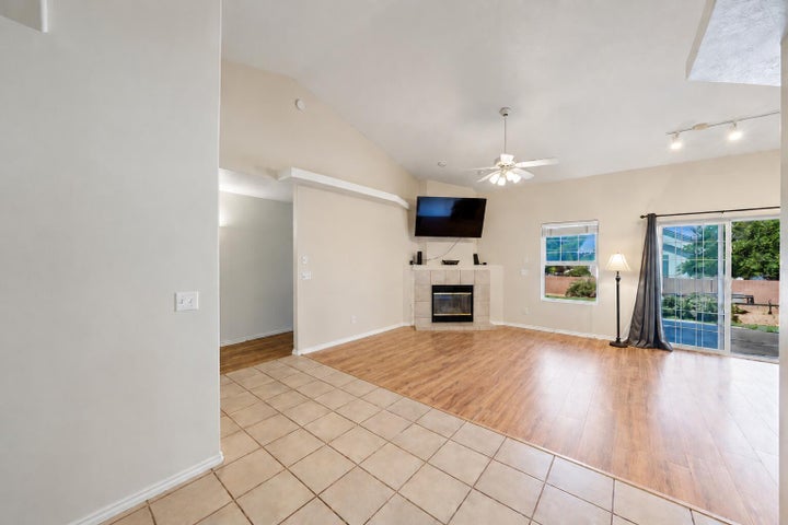 Living area with vaulted ceilings, a fireplace with tile surround, wood-finish flooring, and sliding glass doors to the exterior