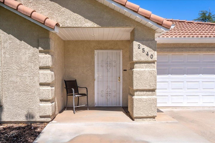 Exterior entry featuring a textured stucco finish, decorative column with house numbers, and a white security screen door