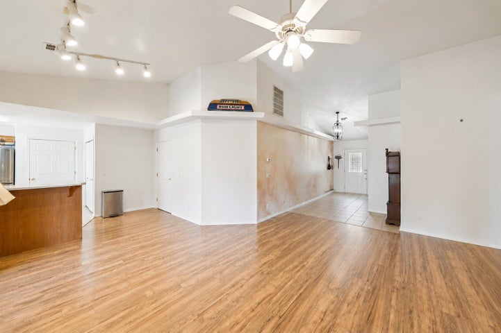 Spacious main living area featuring wood-finish flooring, vaulted ceilings, and a ceiling fan