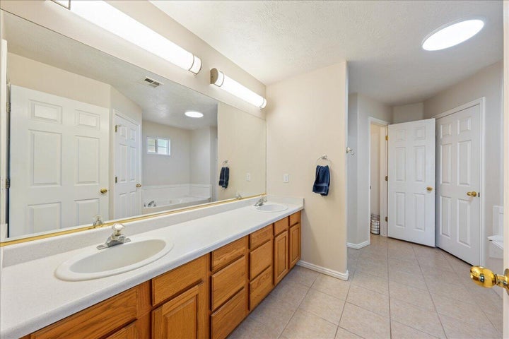 Bathroom featuring a double vanity with wood-finish cabinetry, a large mirror, and dual light fixtures