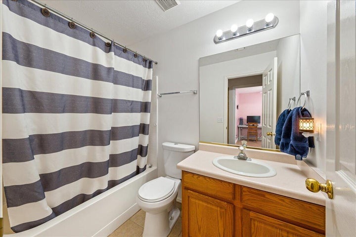 Full bathroom featuring a white tub, toilet, and a wood-finish vanity with a single sink