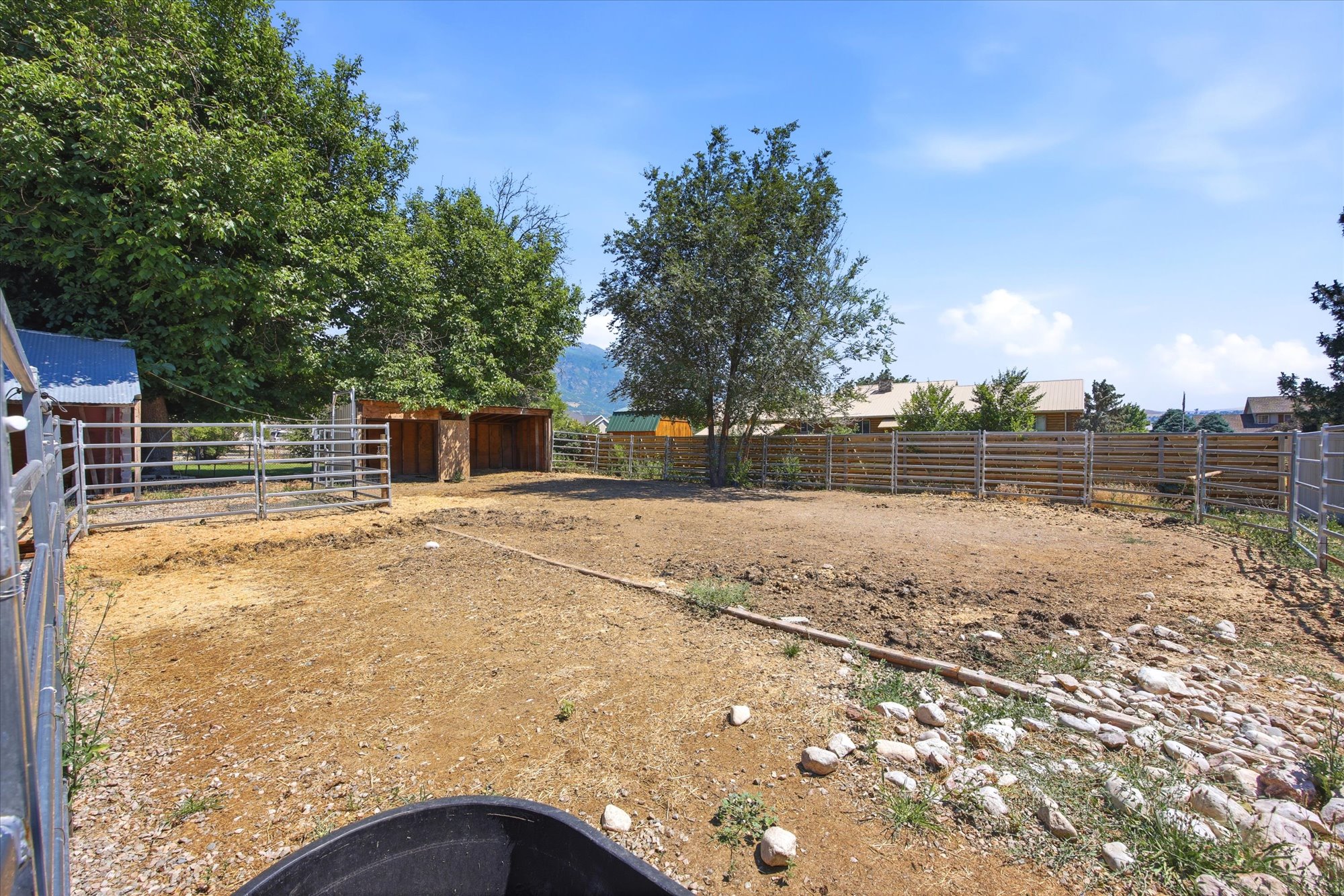 Expansive fenced area featuring metal panel fencing and wood fencing