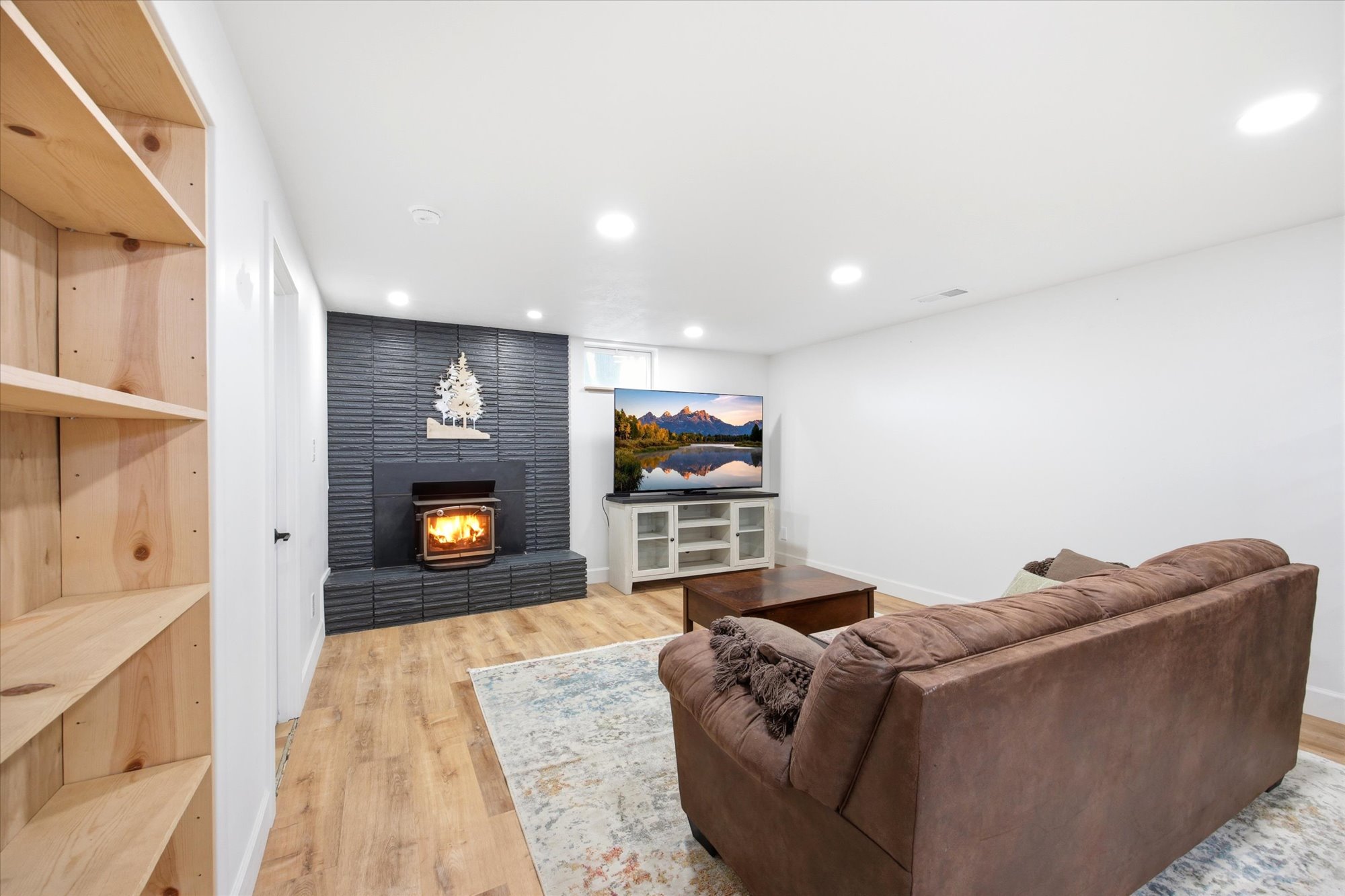 Living area featuring a dark brick fireplace, recessed lighting, wood-finish flooring, and built-in shelving