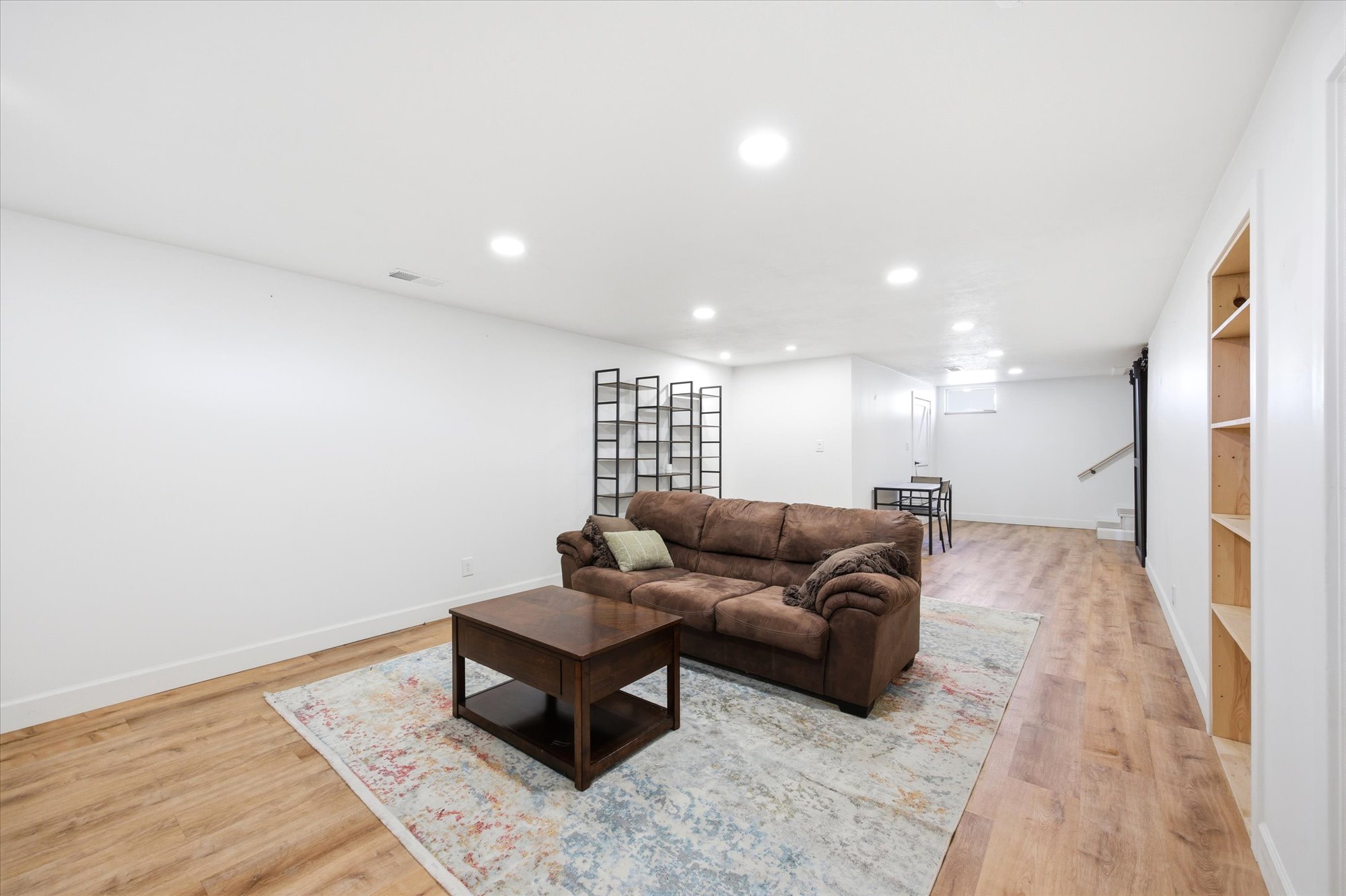 Spacious entertainment area featuring wood-finish flooring, recessed lighting, and built-in shelving