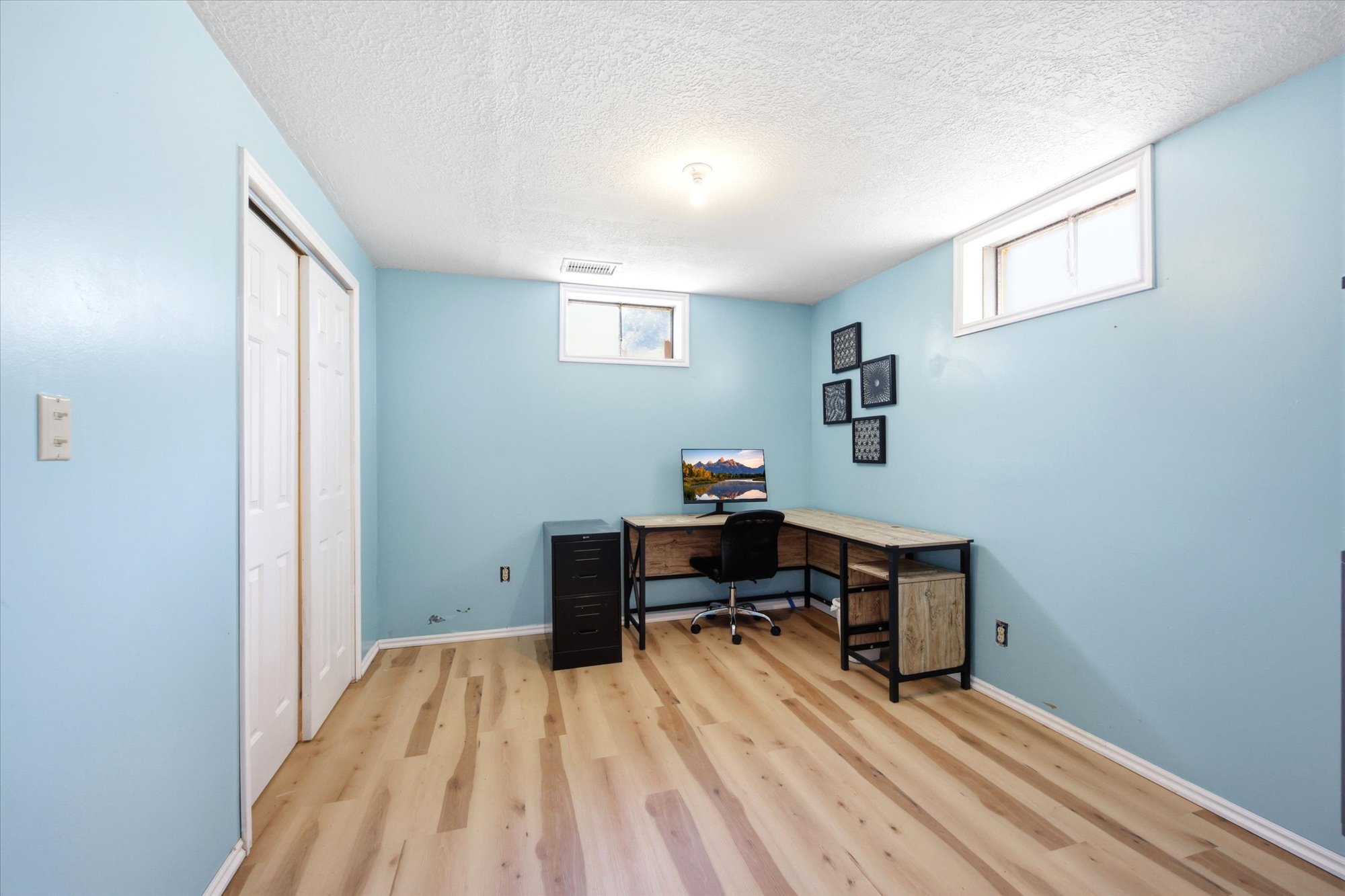 Light wood-finish flooring compliments the blue walls in this room and white bi-fold closet doors. New LVP flooring