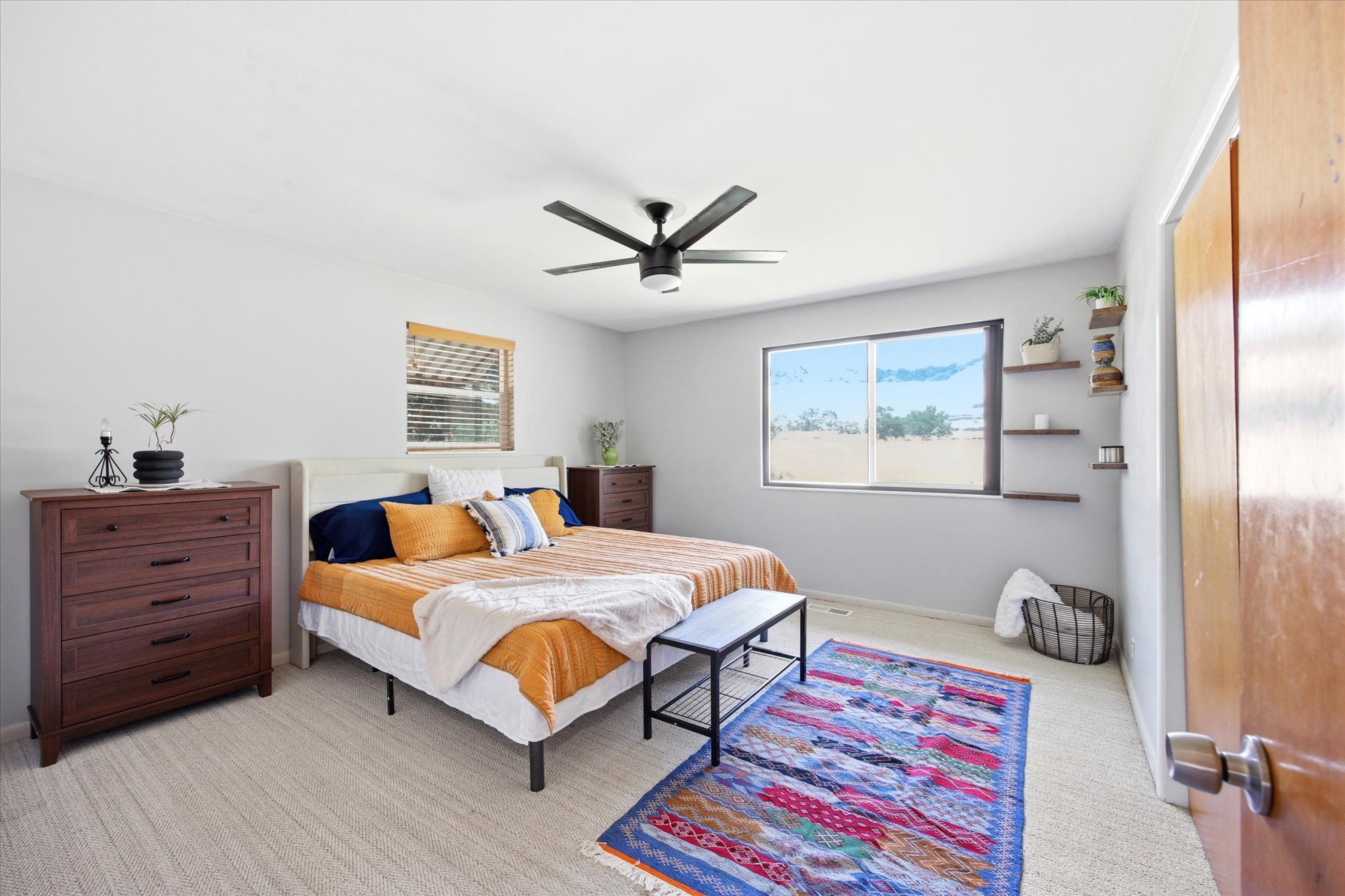 Spacious room with light-colored carpeting, a large window offering natural light, and a ceiling fan and views of the mountains.