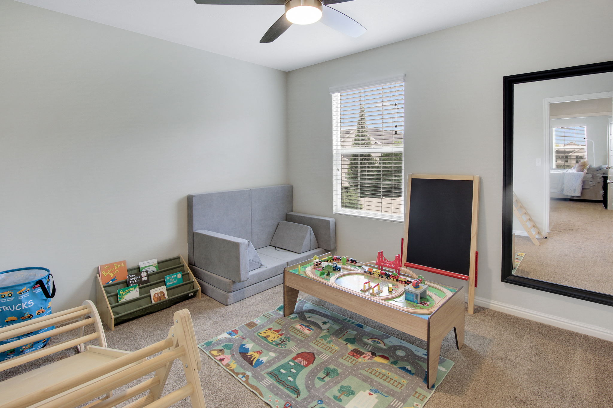 Carpeted room featuring a ceiling fan with integrated lighting, a window with horizontal blinds, and a large wall-mounted mirror