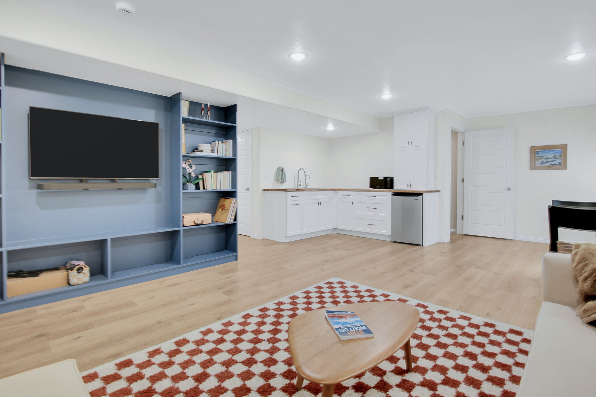 Open-concept living space featuring wood-finish flooring, a built-in media center with shelving, and recessed lighting