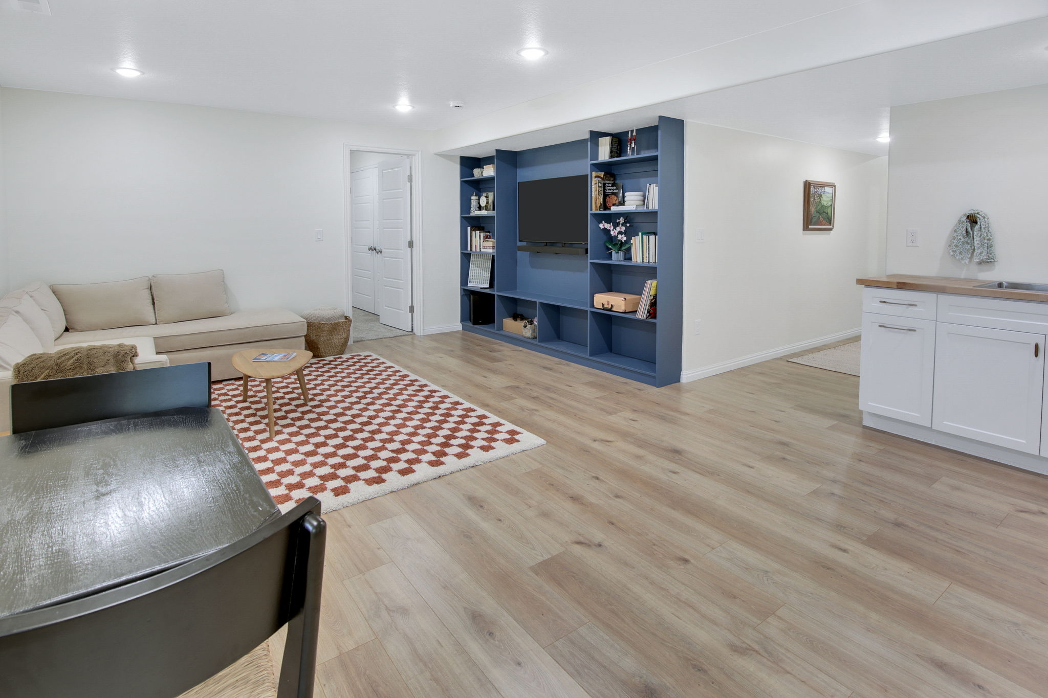Open concept living area featuring wood-finish flooring, recessed lighting, a built-in media center with shelving, and a wet bar with white cabinetry and a wood countertop