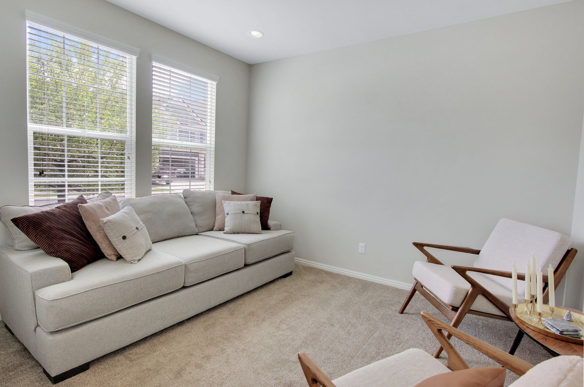 Bright living area featuring two large windows with blinds, recessed lighting, neutral wall tones, and carpet flooring