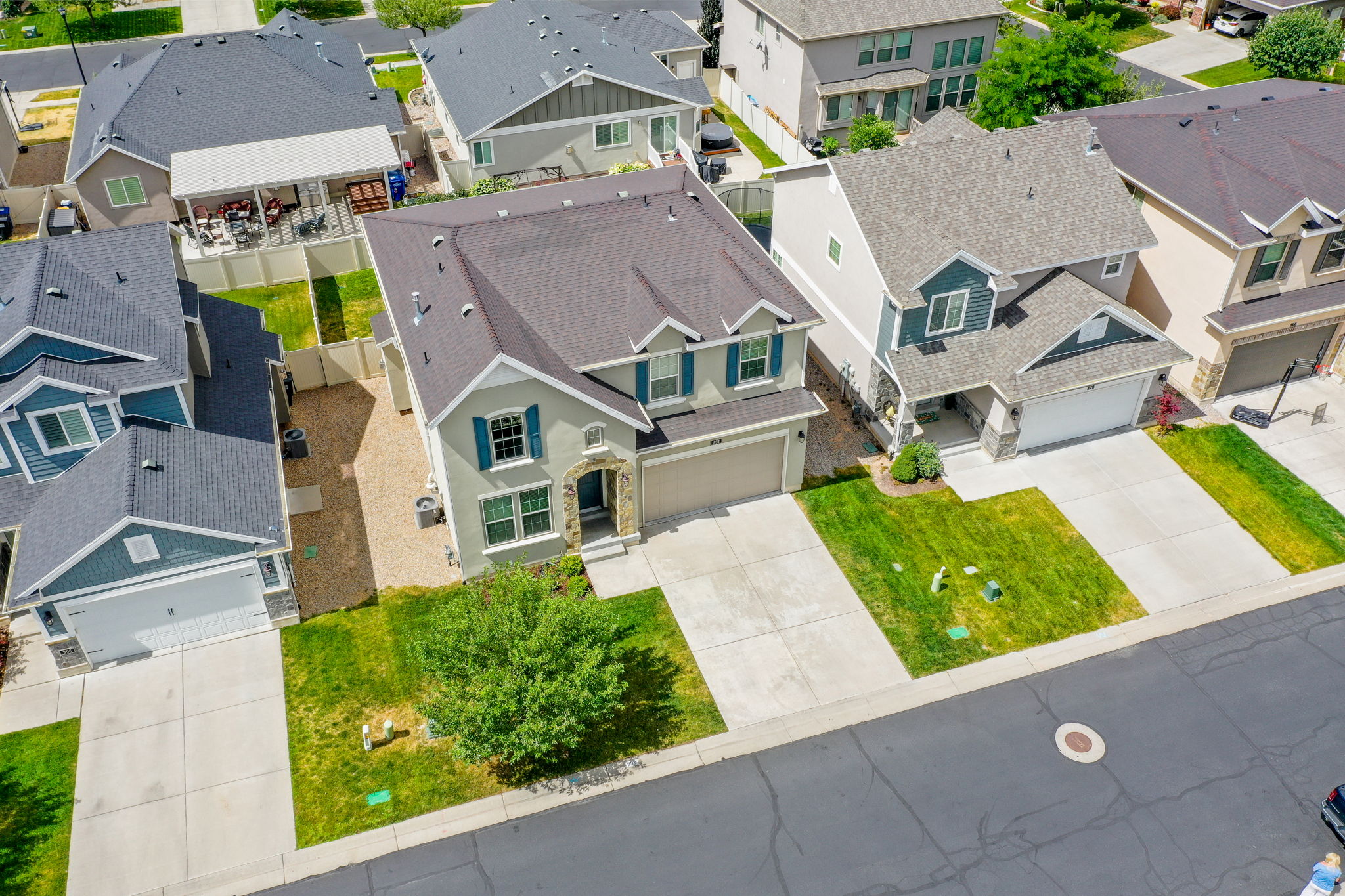 Two-story residence featuring a two-car garage, stone and stucco facade, decorative window shutters, and a well-maintained front lawn