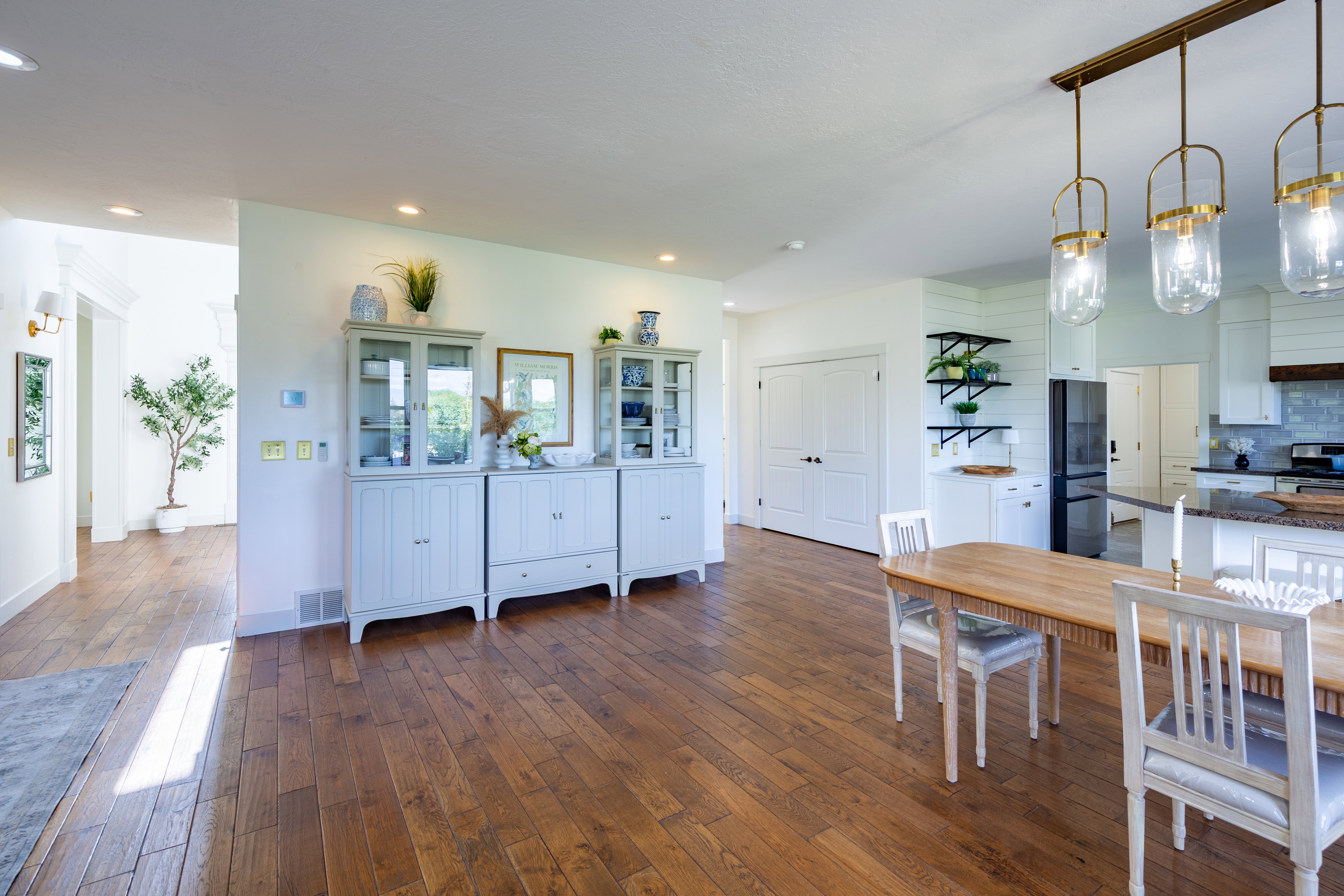Expansive wood-finish flooring throughout, complemented by recessed lighting and a contemporary chandelier