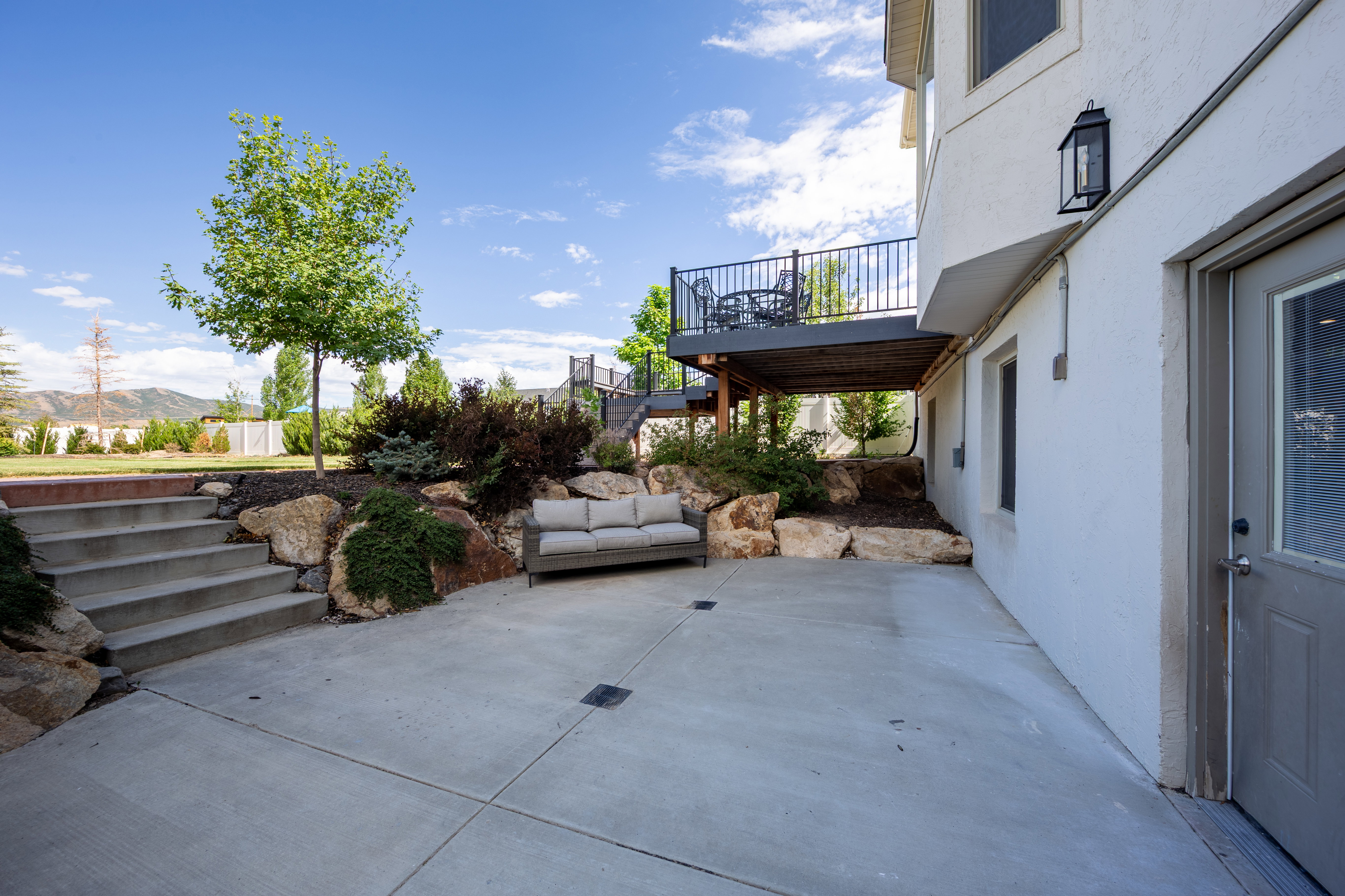 Expansive concrete patio area with integrated steps and a landscaped rock garden