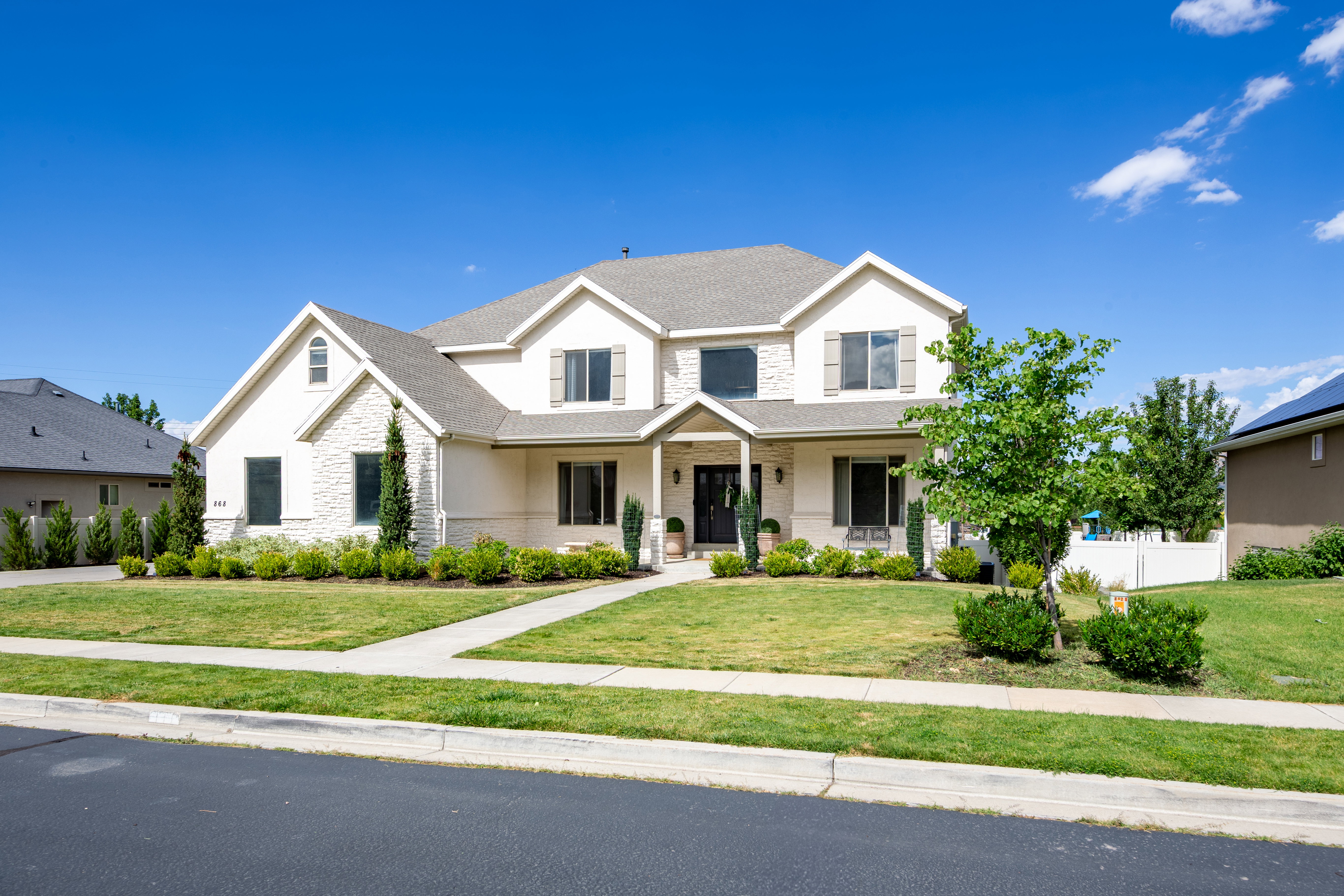 Two-story residence featuring a combination of stone and stucco exterior finishes, a covered porch entry, and a pitched roofline