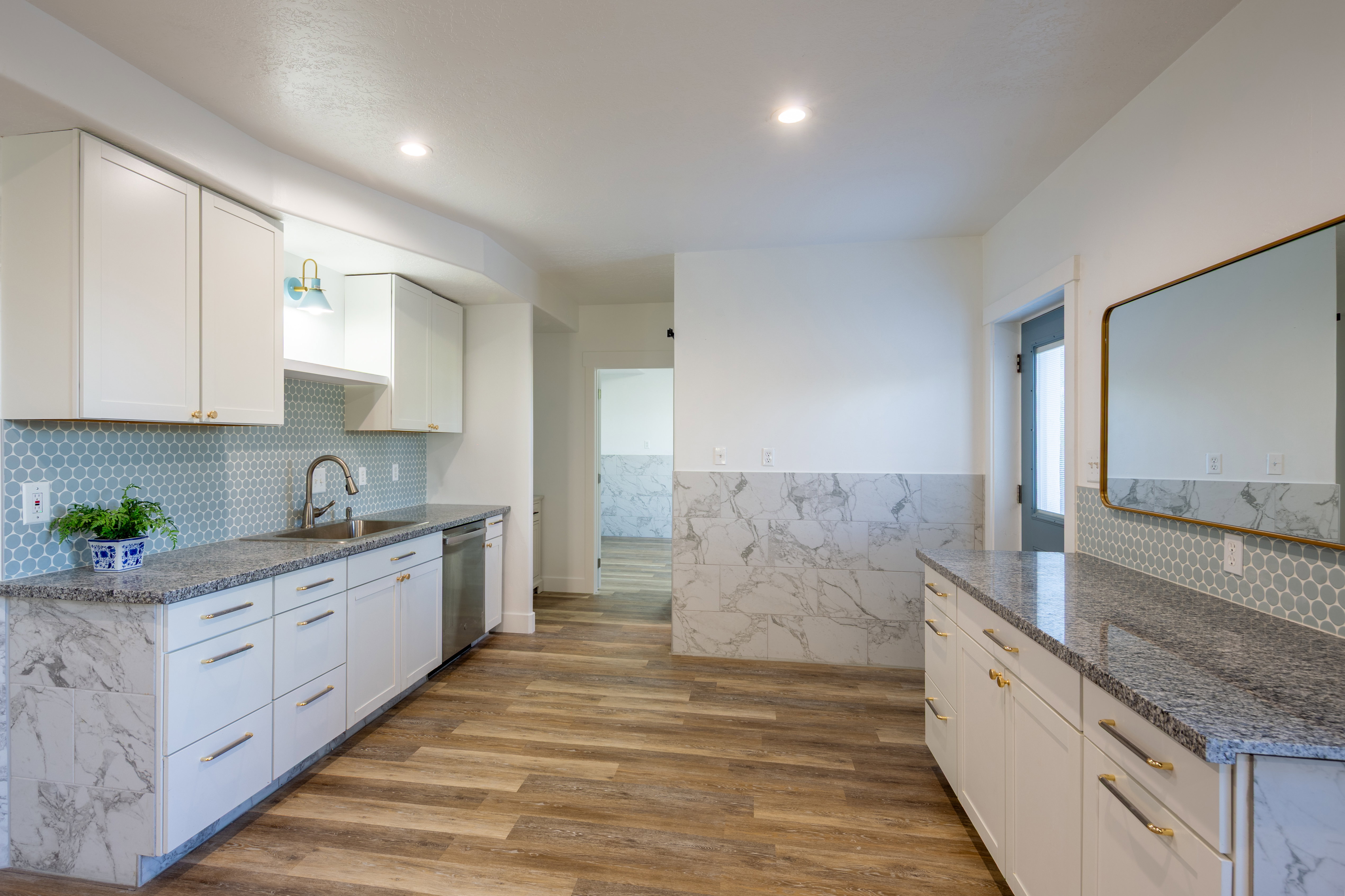 Kitchen featuring white cabinetry with gold-toned hardware, granite countertops, and a blue penny tile backsplash
