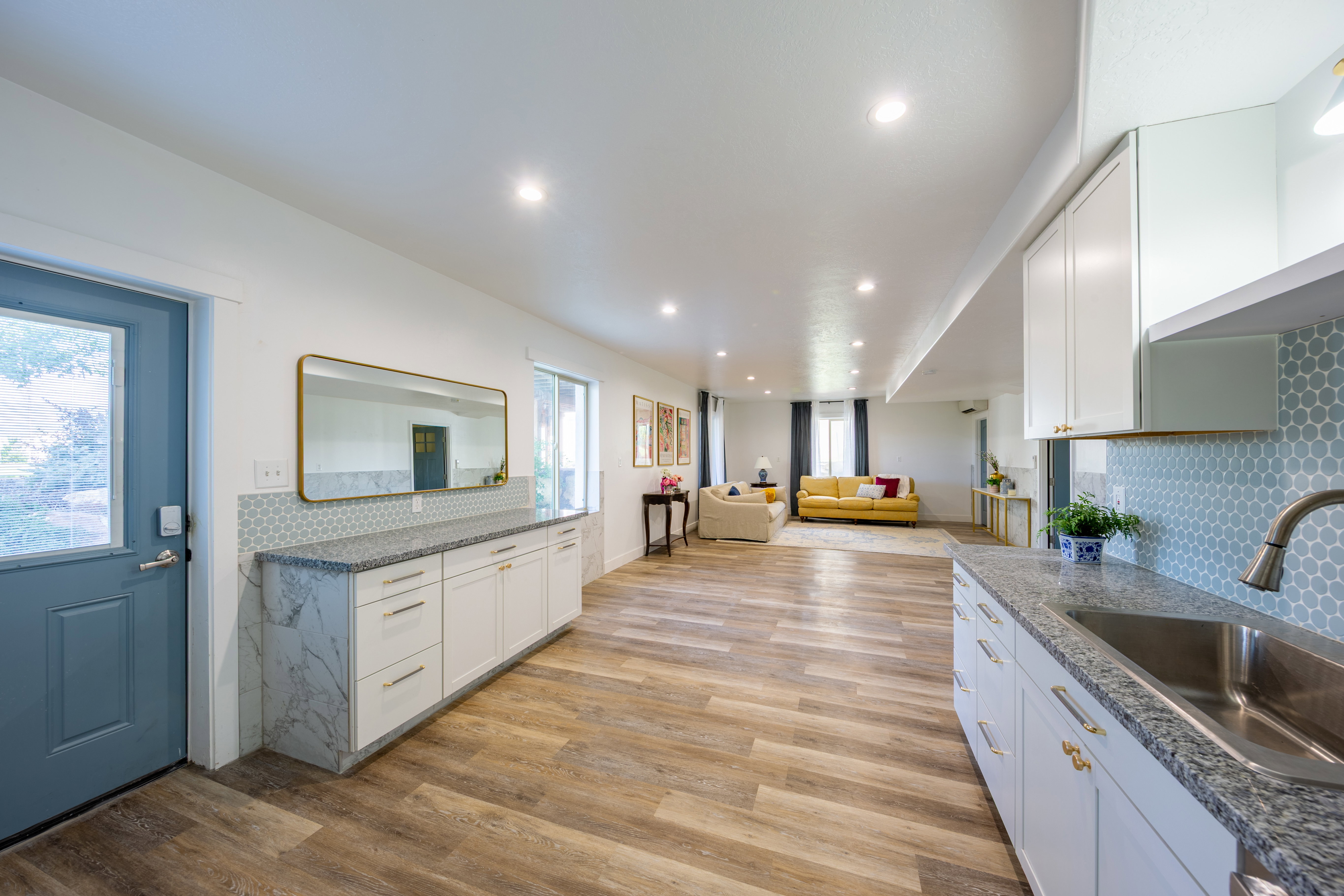 Expansive interior featuring wood-finish flooring, recessed lighting, and a kitchen area with white cabinetry and a stainless steel sink