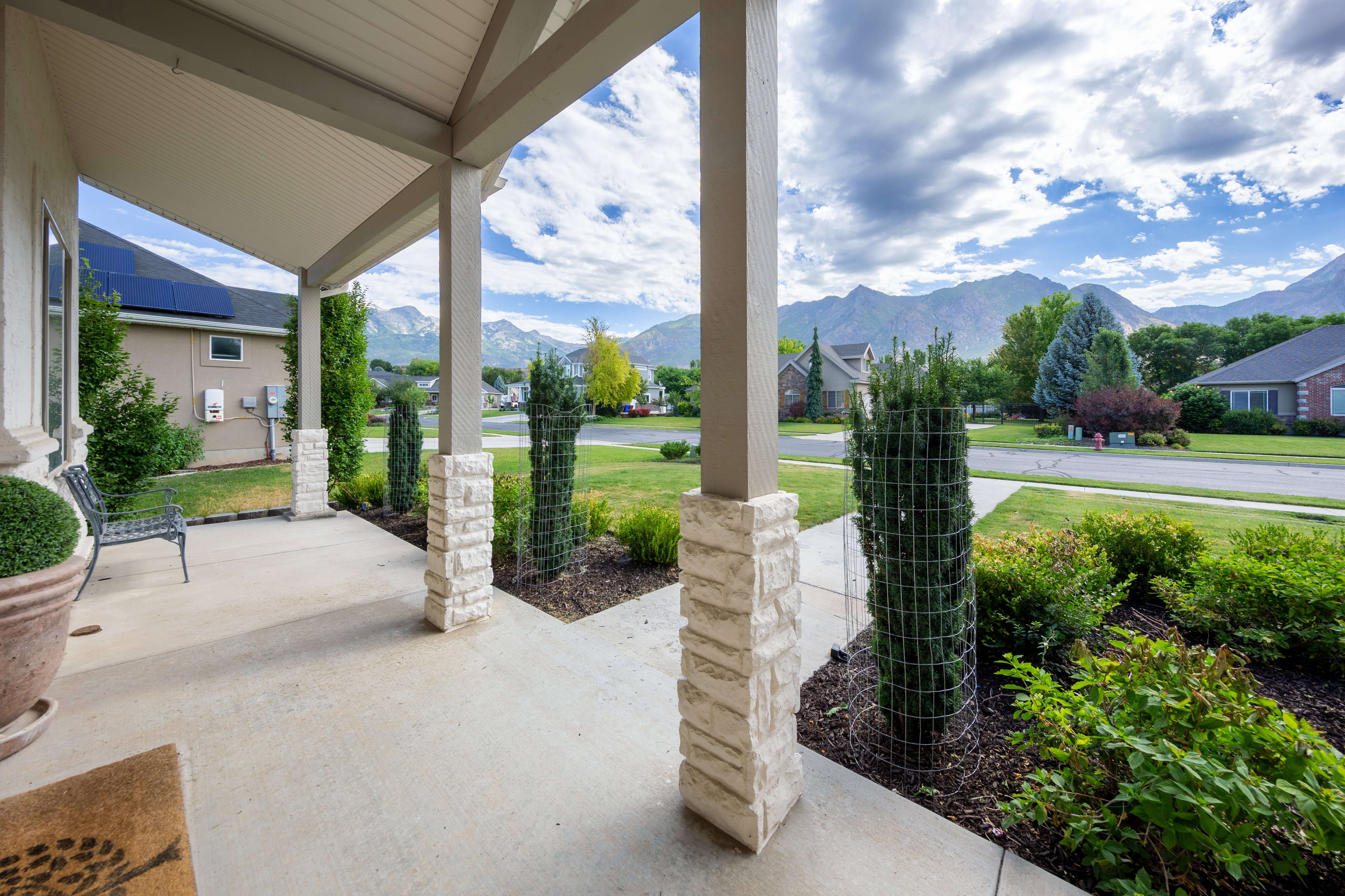 Covered front porch featuring stacked stone columns and a concrete surface