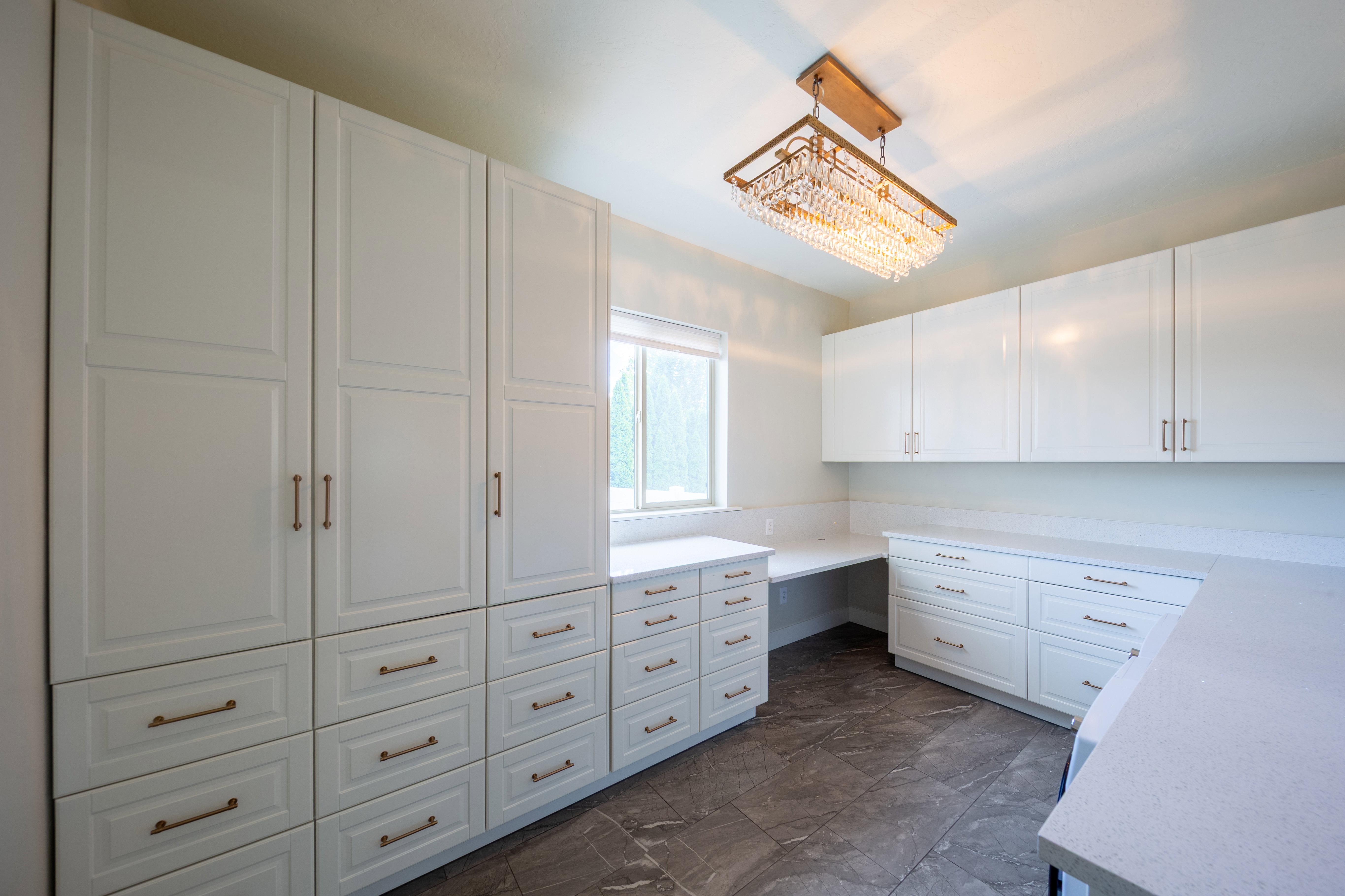 Spacious room featuring extensive white cabinetry with varied storage options, including full-height pantry-style units and multiple drawers