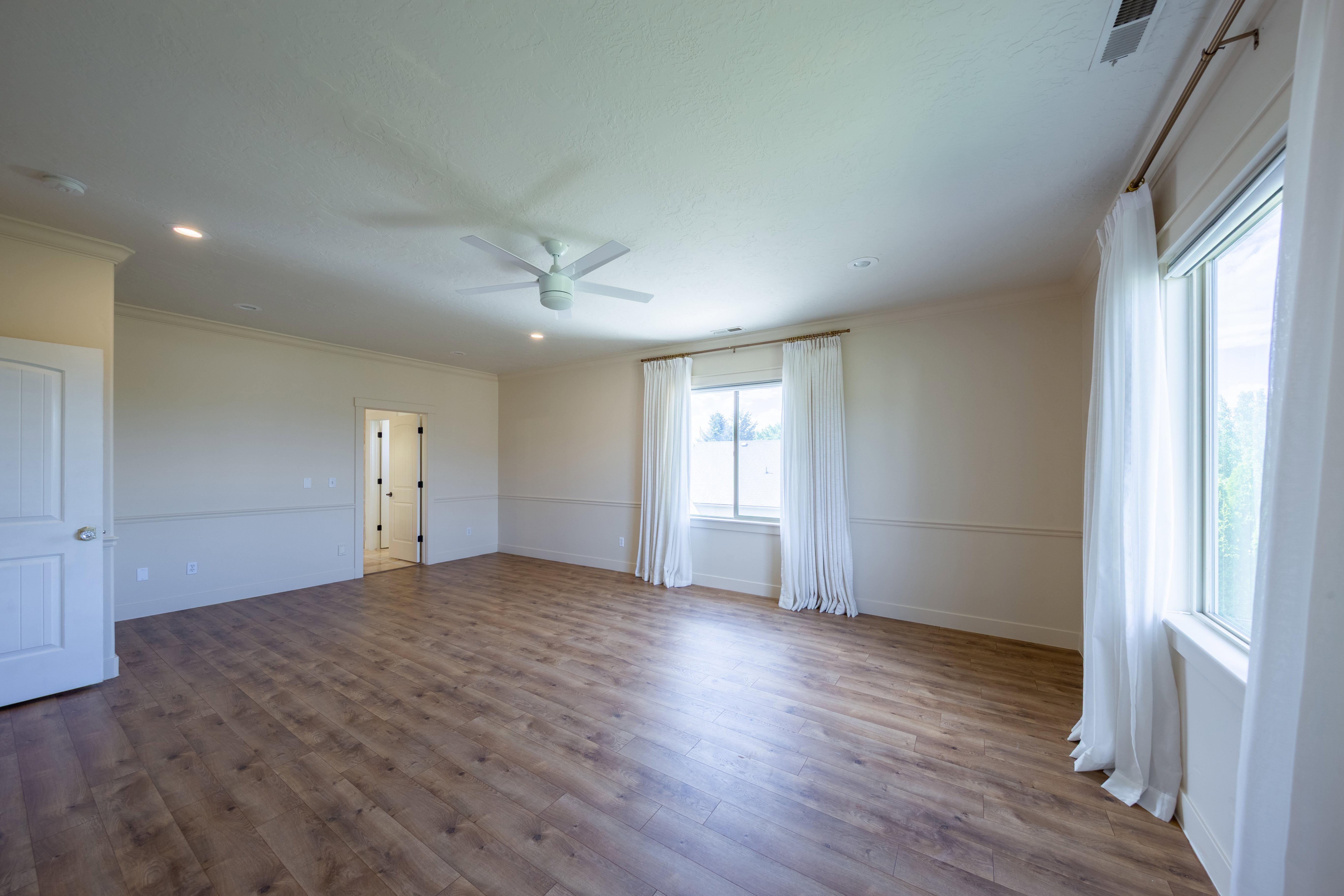Spacious room featuring wood-finish flooring, recessed lighting, and a ceiling fan