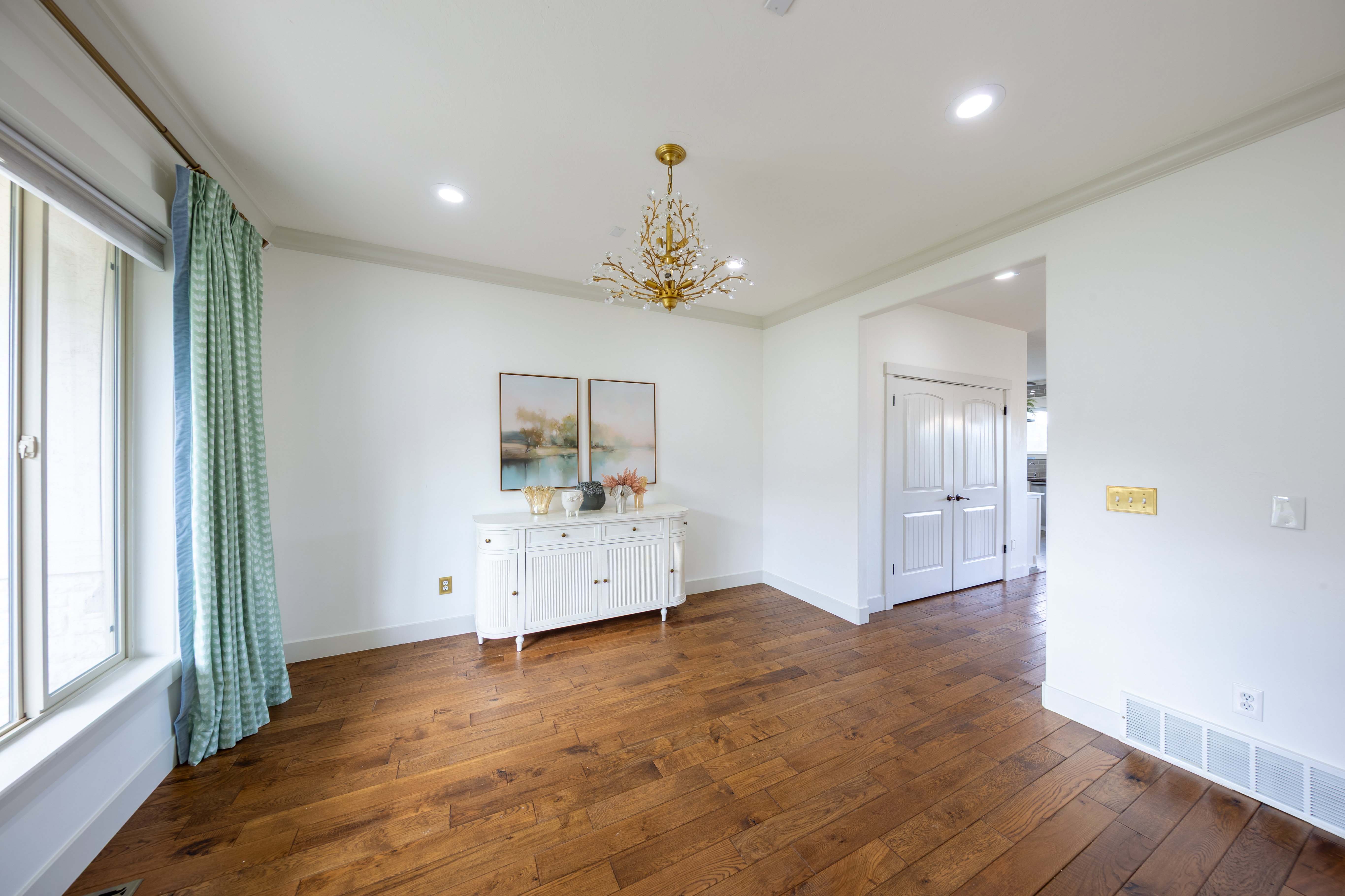 Spacious room featuring wood-finish flooring, a contemporary chandelier, recessed ceiling lighting, crown molding, and white baseboards