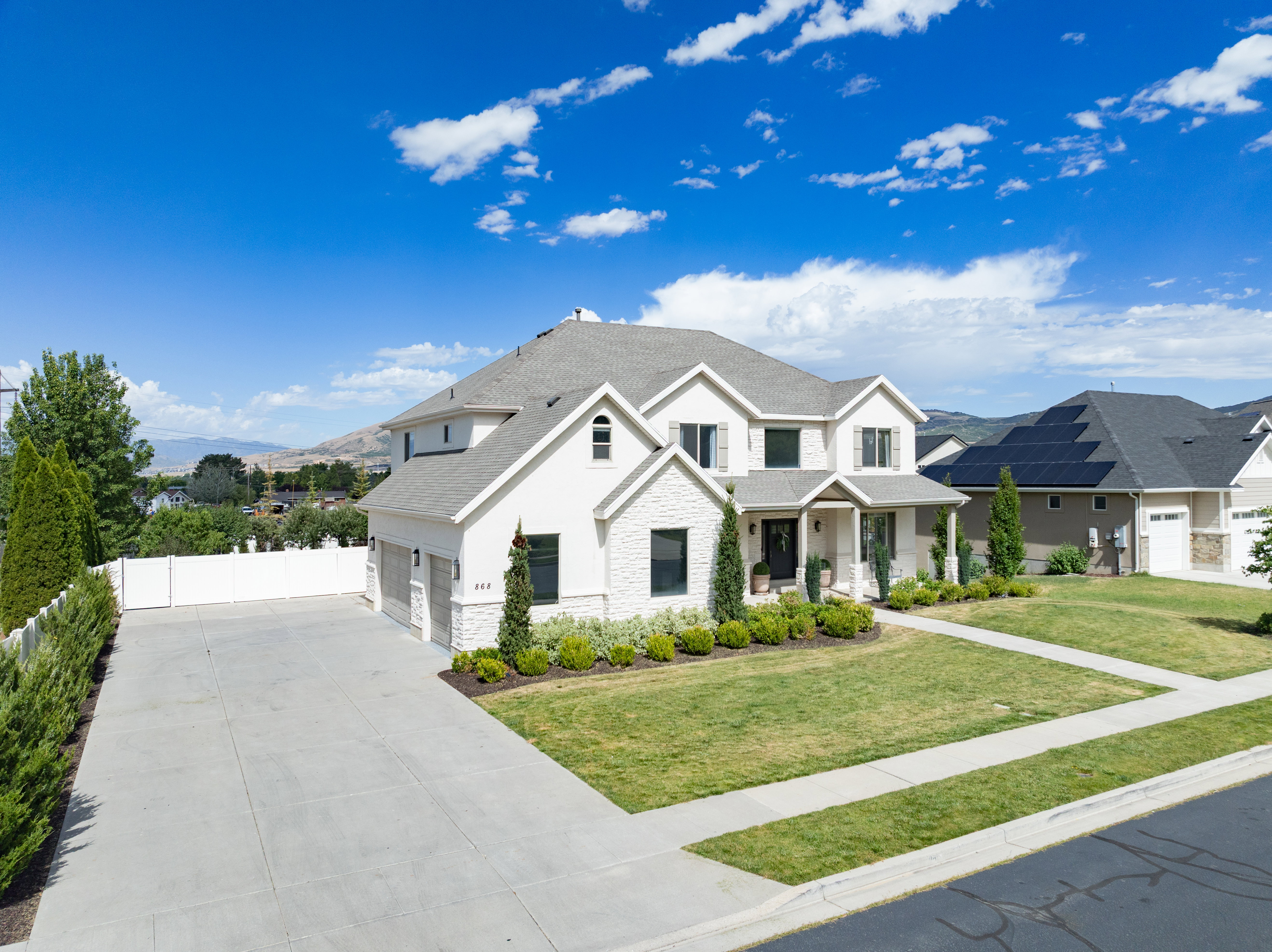 White stucco and stone facade residence featuring a covered entry, multiple gables, and a two-car garage