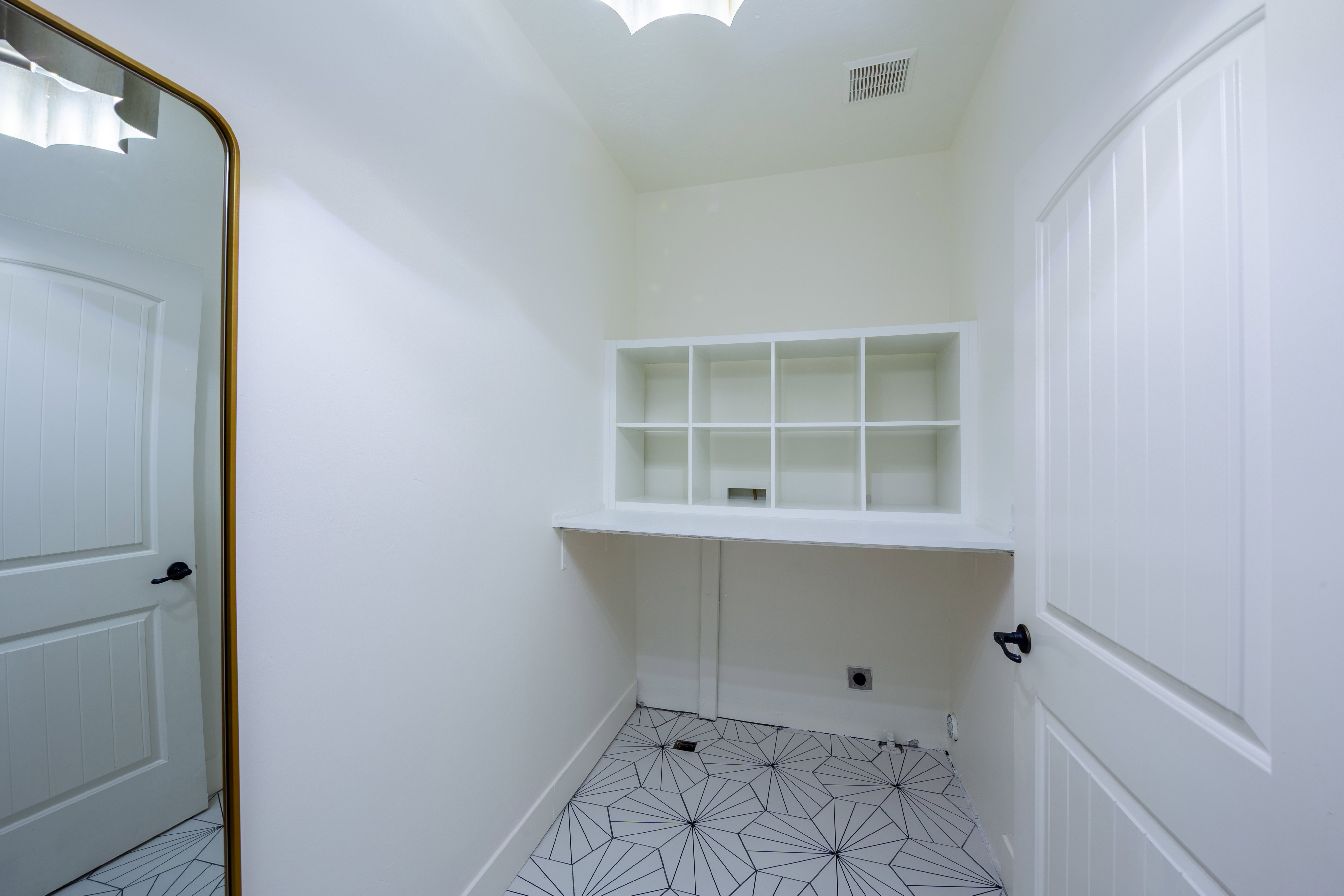 Built-in shelving with cubby storage, white countertop, geometric tile flooring, and white paneled doors