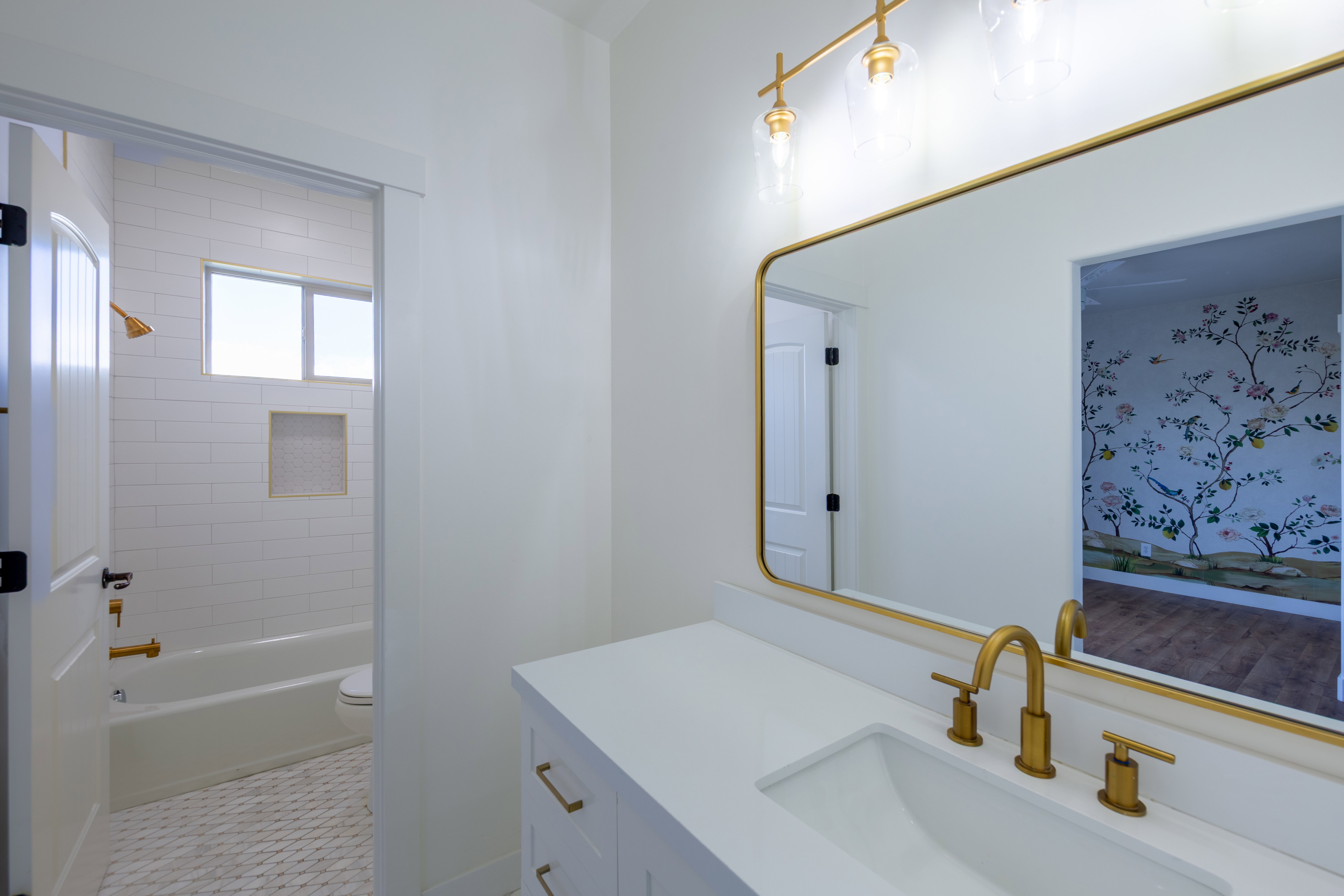 Contemporary bathroom featuring a white vanity with integrated sink, gold-finish fixtures, and a large framed mirror