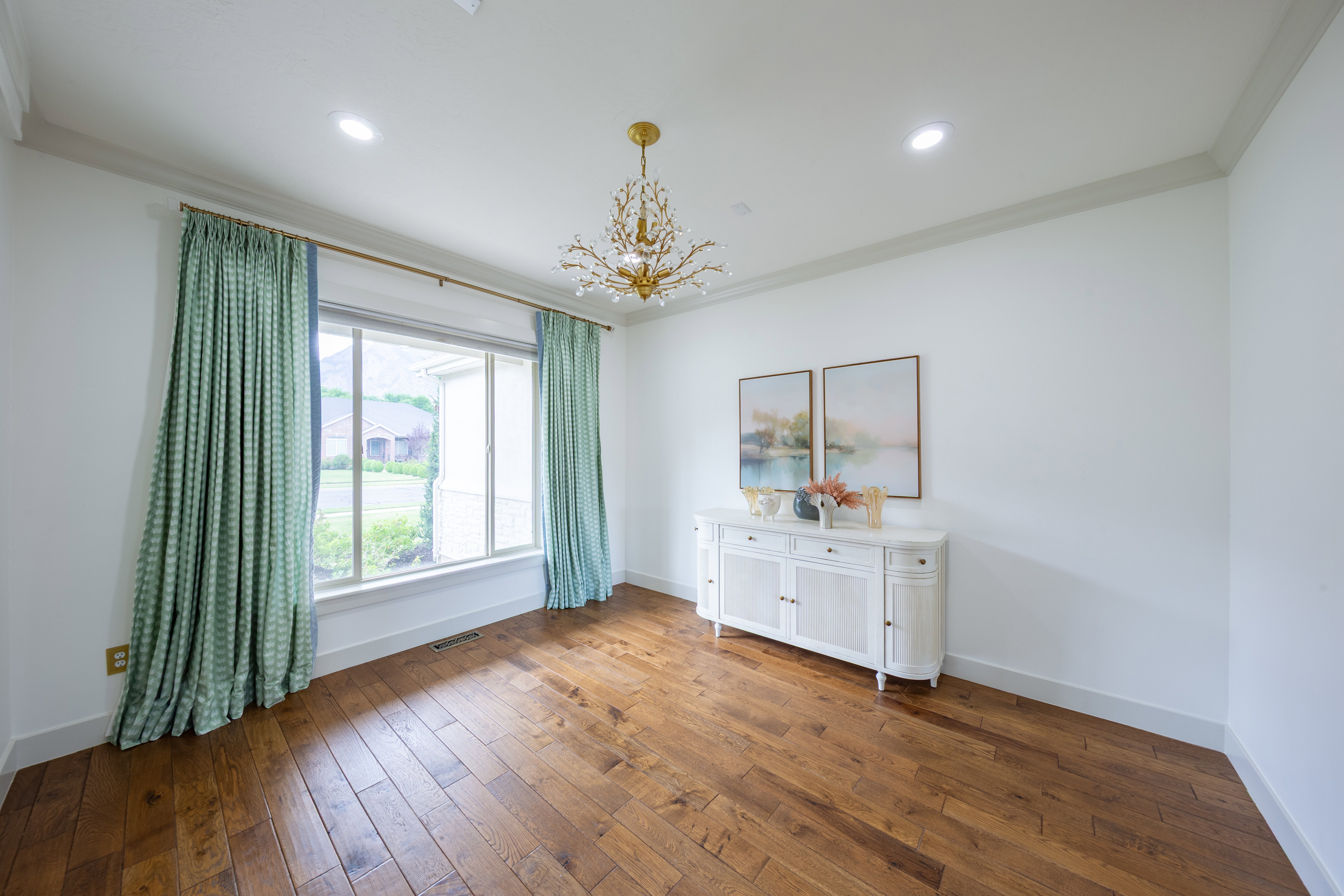 Spacious room featuring wood-finish flooring and a contemporary chandelier