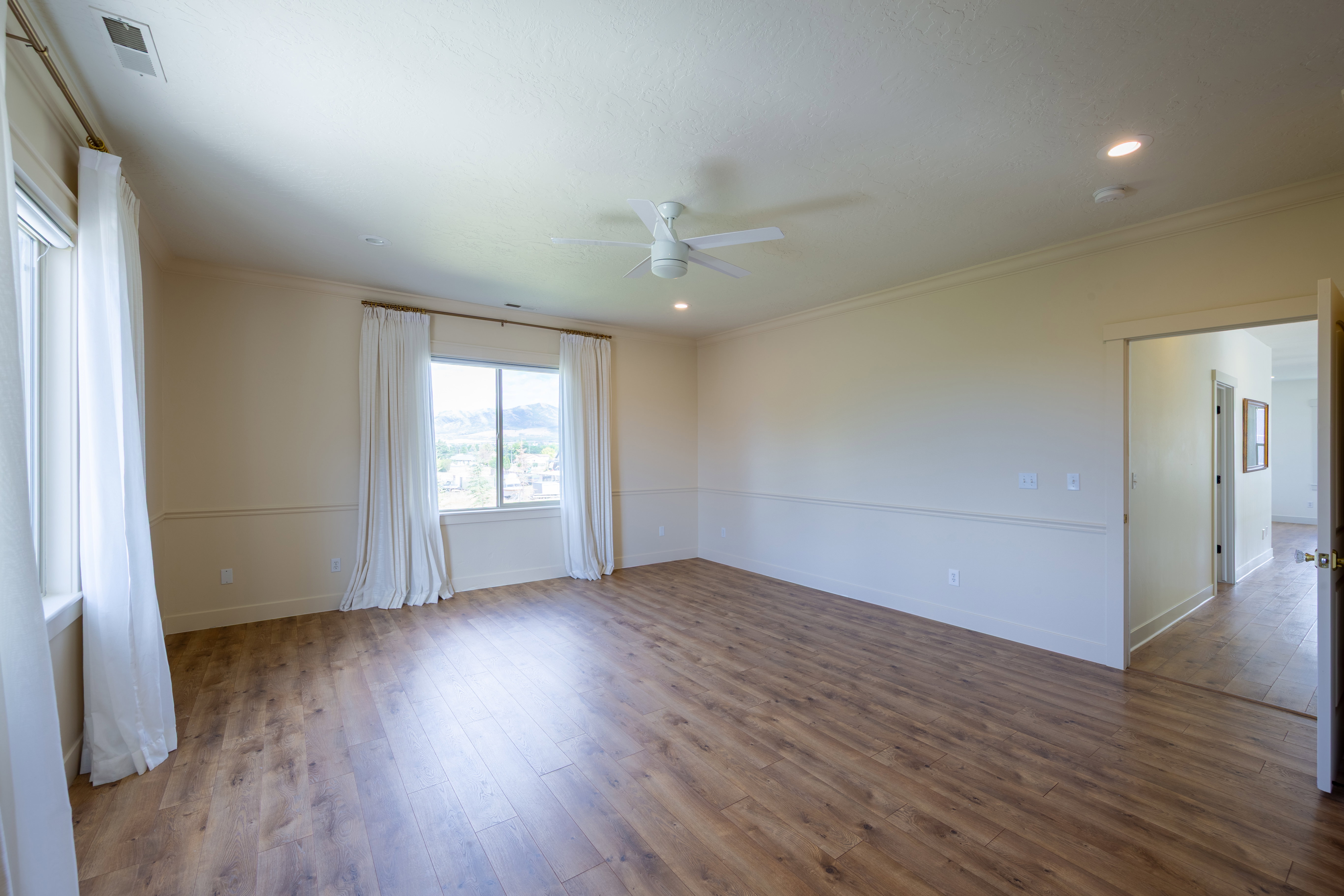 Spacious room featuring wood-finish flooring, multiple windows, a ceiling fan, and recessed lighting